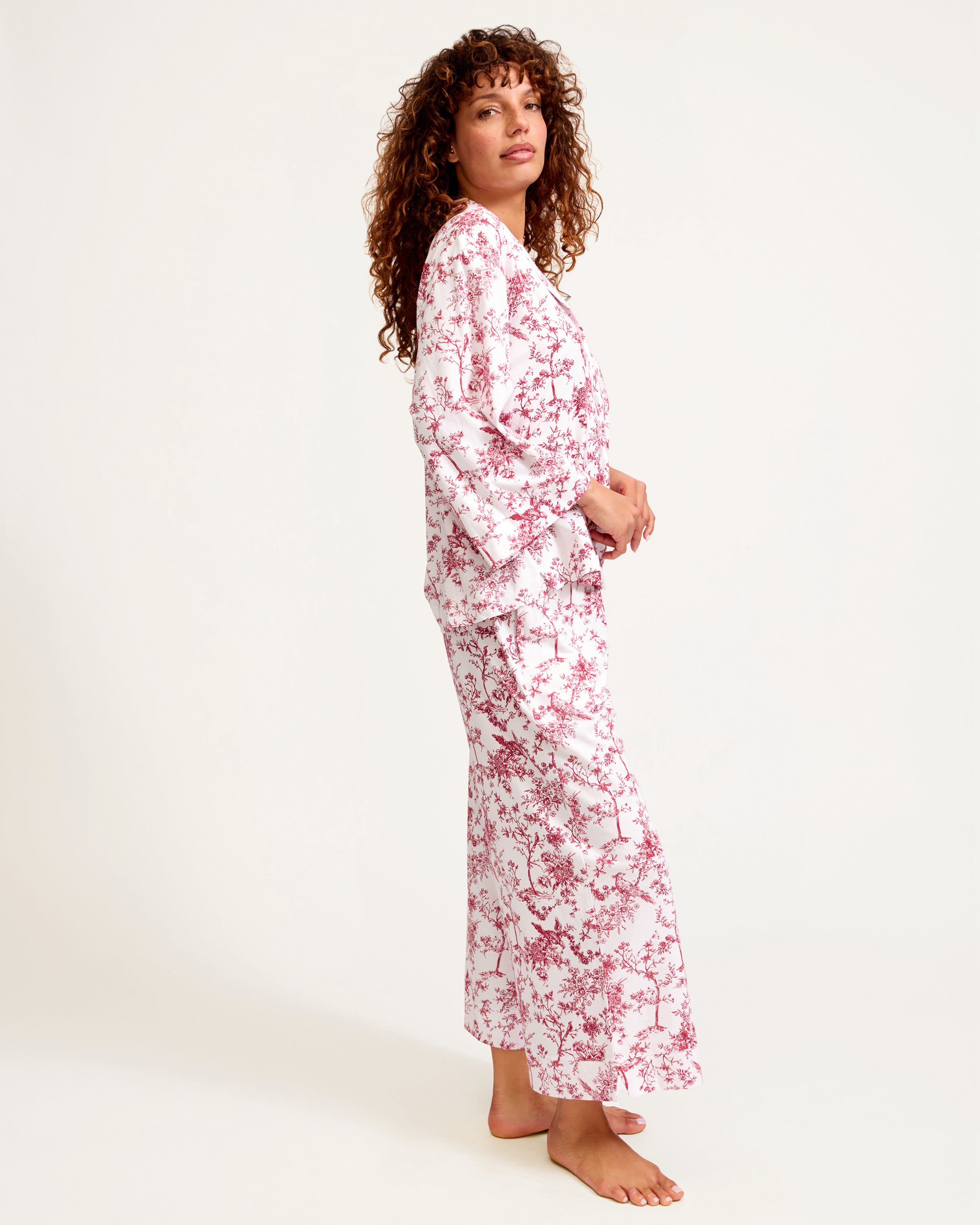 The Olivia Wide Leg Pima Pajama Set in Red Timeless Toile features a long-sleeve button-up shirt and pants with a white background and a red floral and tree branch design.