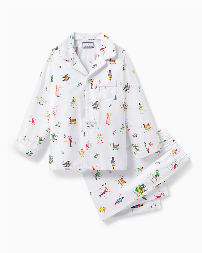 A set of white pajamas with colorful, playful illustrations of people, animals, and plants. The set includes a long-sleeve button-up top with a collar and a front pocket, and matching pants with an elastic waistband.