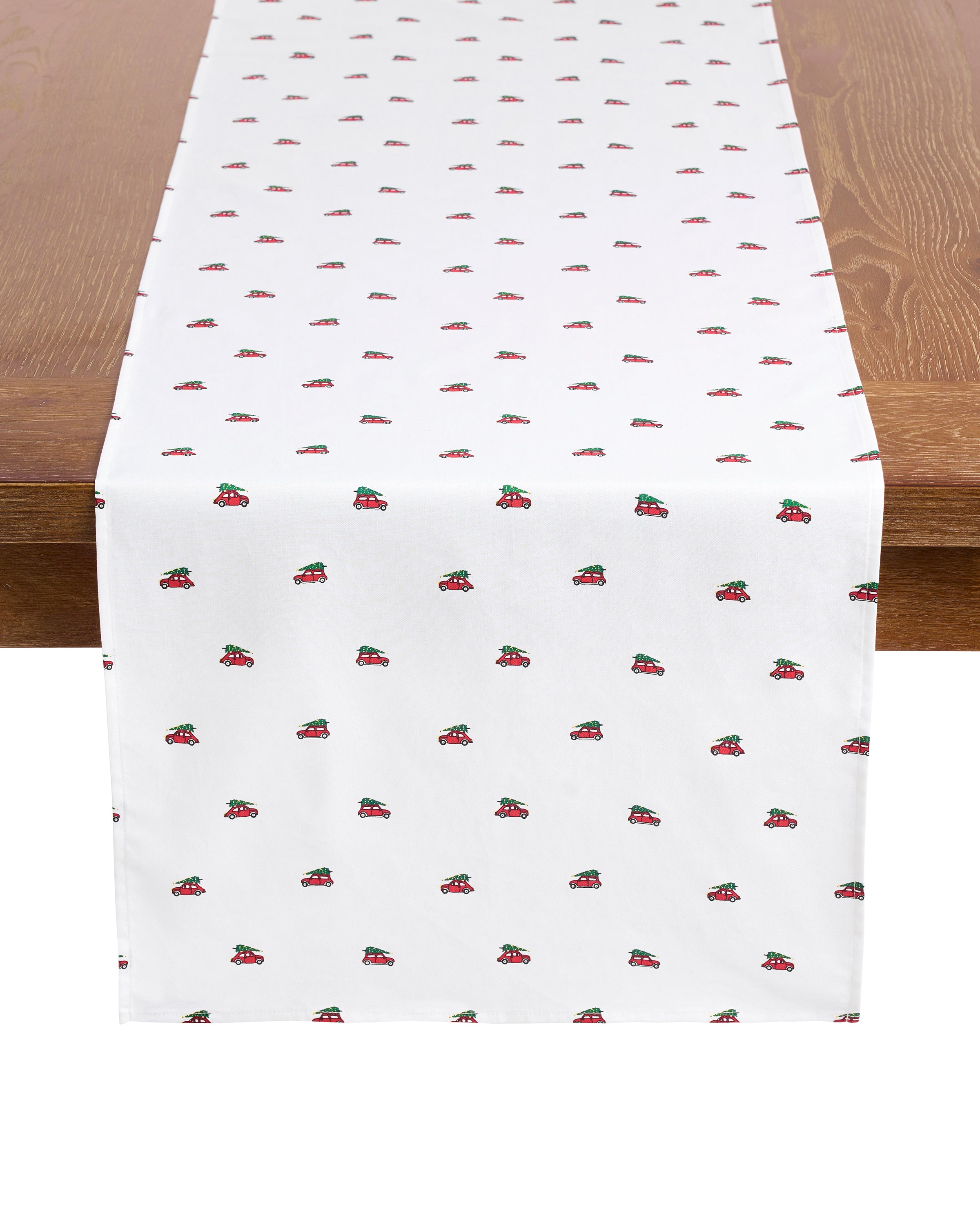A wooden table is adorned with Petite Plumes Signature Twill Table Runner in Holiday Journey, a white 100% cotton design featuring vibrant strawberries, perfect for a festive tablescape on any occasion.
