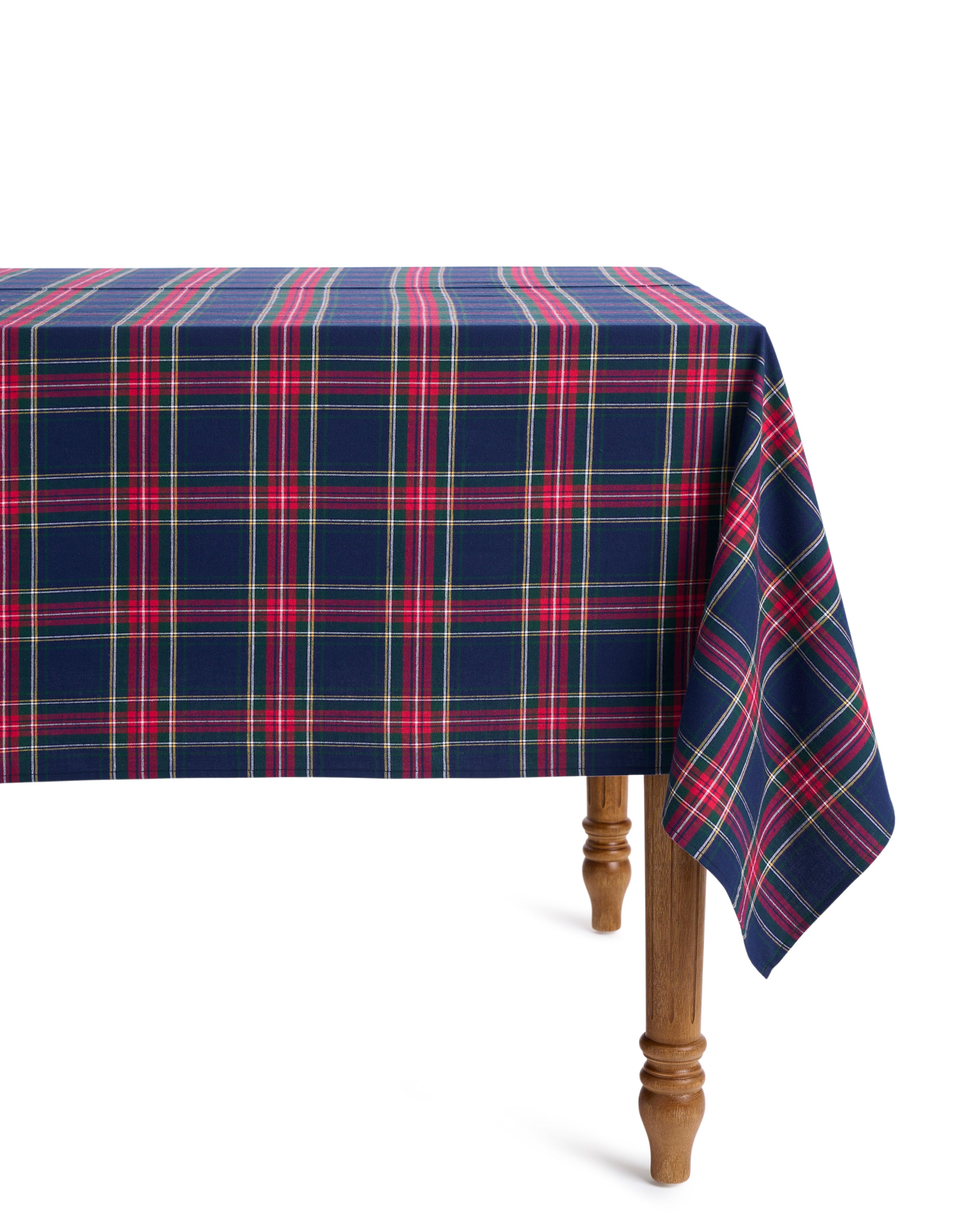 A festive tablescape is created with Petite Plumes Signature Twill Tablecloth in Windsor Tartan, featuring 100% cotton in red, green, and blue plaid. The wooden legs support the cloths vibrant drop on one side, making it perfect for holiday gatherings.