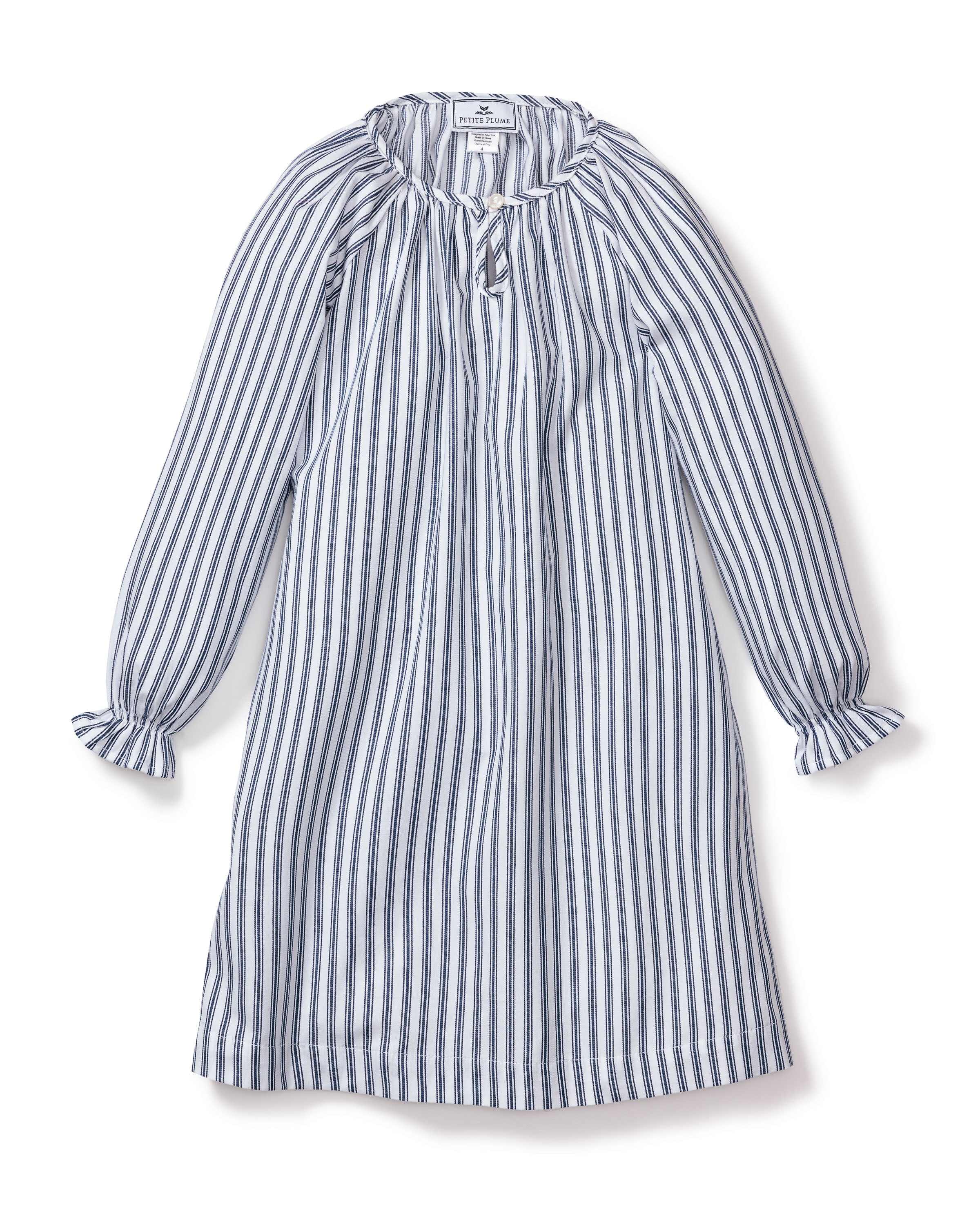 The Petite Plume Girls Twill Delphine Nightgown in Navy French Ticking has a loose fit with ruffled cuffs, vertical stripes, a gathered neckline with keyhole detail, and a relaxed silhouette. It is perfect for childrens sleepwear and crafted from flame-retardant fabric.