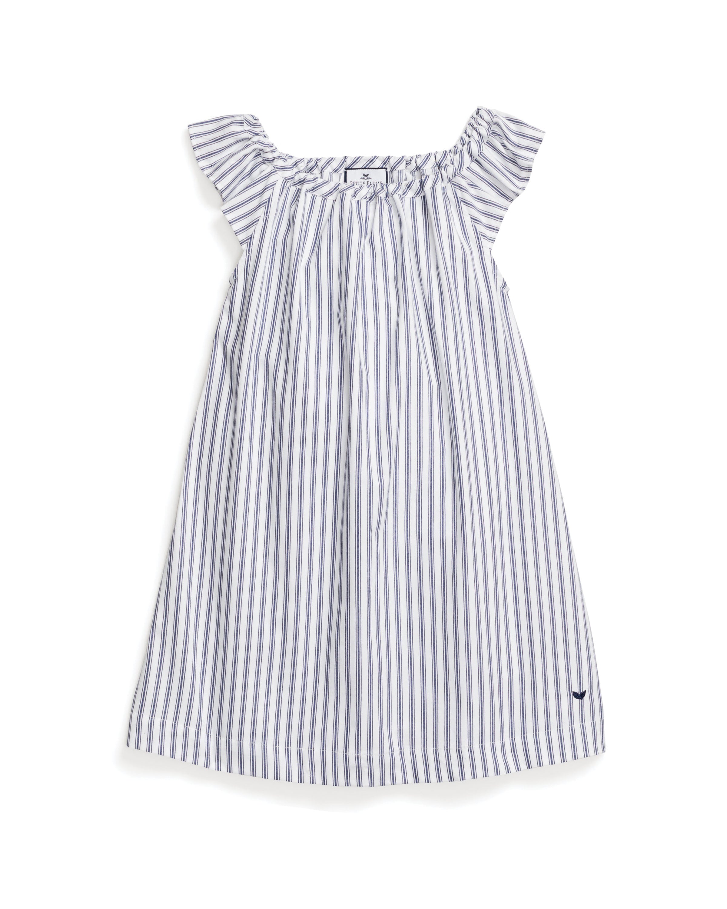 The Girls Twill Isabelle Nightgown by Petite Plume in Navy French Ticking is made of yarn-dyed cotton with light gray and white stripes, featuring ruffled shoulders and a small dark blue embroidered logo near the hem for a loose, flowing fit.