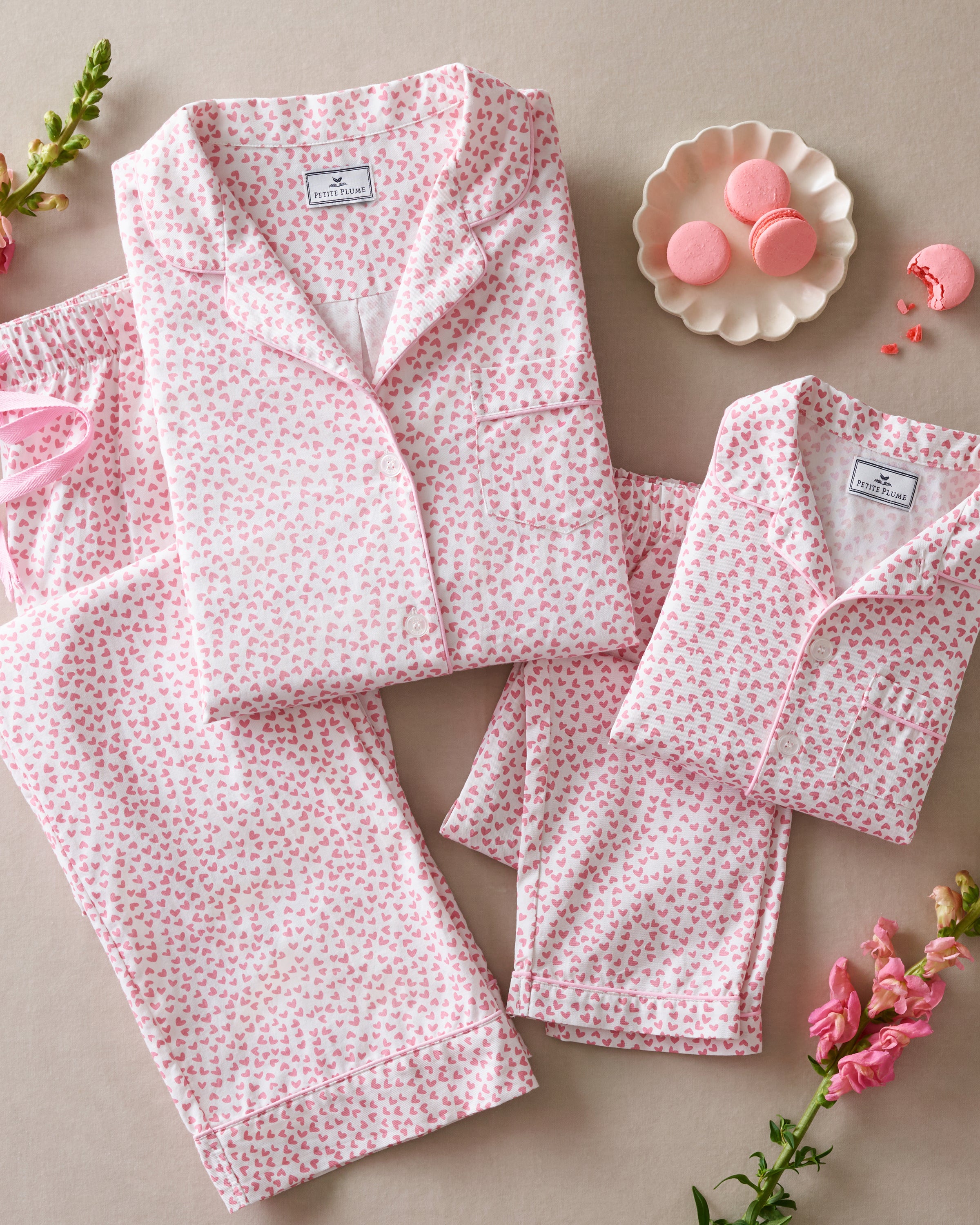 The Kids Twill Pajama Set in Sweethearts by Petite Plume features a pink and white floral pattern with a button-up top and matching pants, crafted from light fabric for a luxurious, cozy experience.