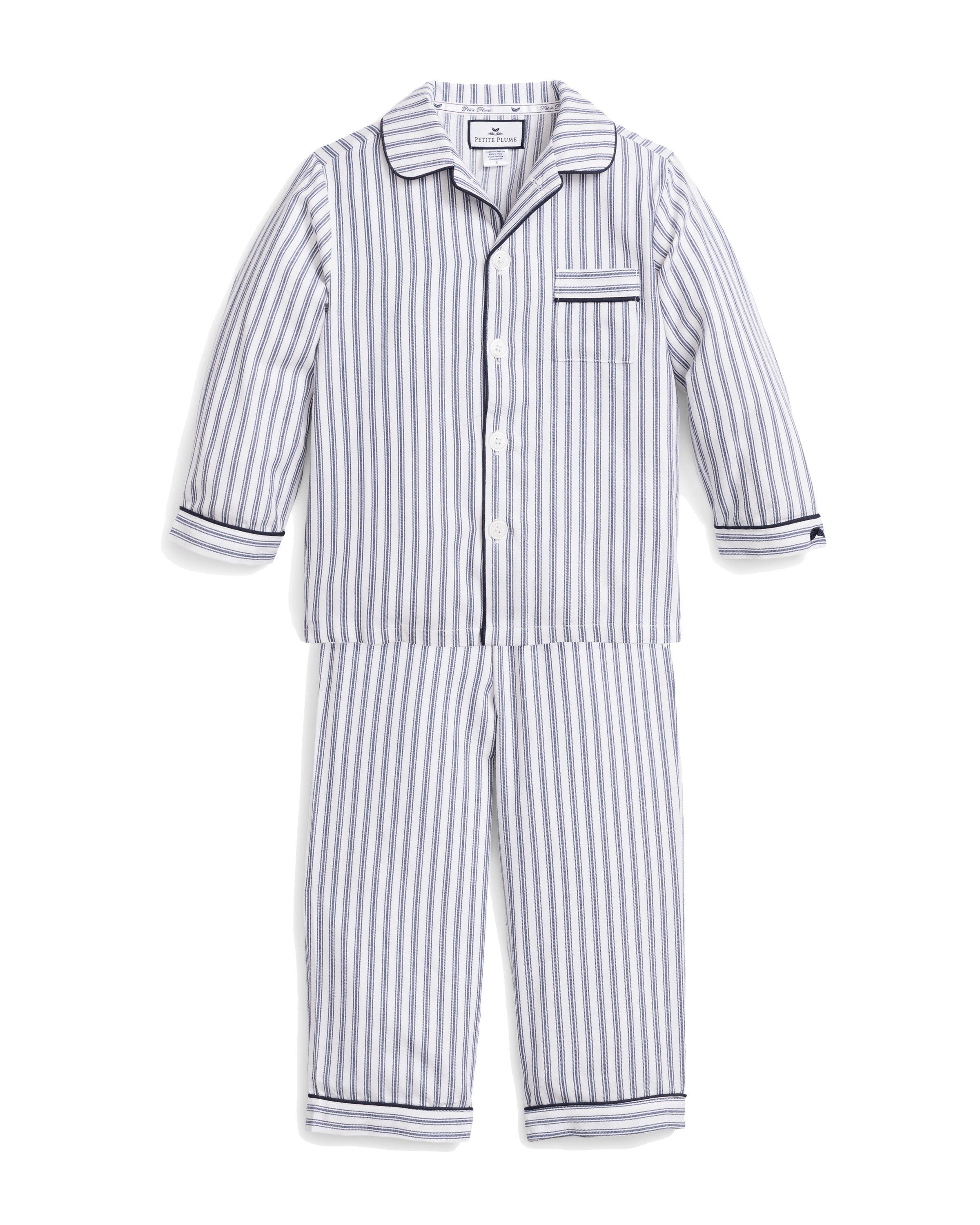 Kid’s Twill Pajama Set in Navy French Ticking: a children’s two-piece pajama set with long sleeves and pants, designed in blue and white vertical stripes with white buttons, a front chest pocket, and cuffs accented by thin navy piping.