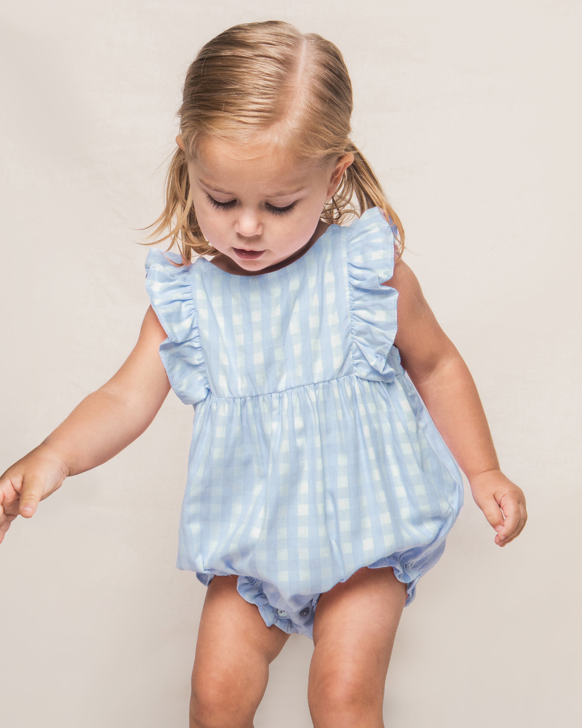 Baby's Twill Ruffled Romper in Light Blue Gingham features ruffled sleeves, a gathered waist, and bottom snap buttons for easy diaper changes, shown on a white background.