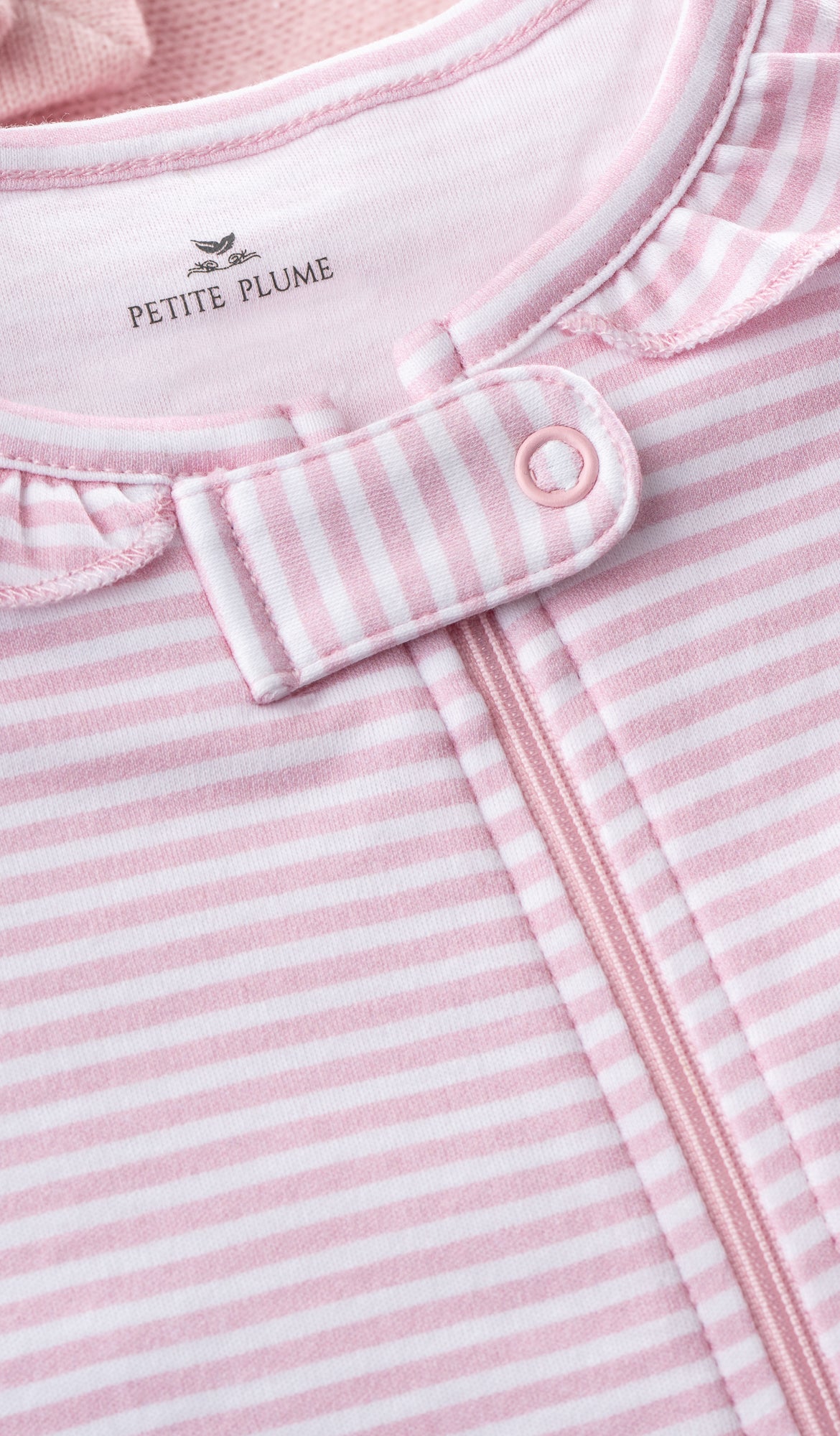 Close-up of Petite Plumes Babys Pima Ruffle Collar Romper in Pink Stripes. Made from soft Pima cotton, it features a zipper, snap button closure, folded collar detail, and subtle ribbed texture to add vibrant colors to your babys wardrobe.