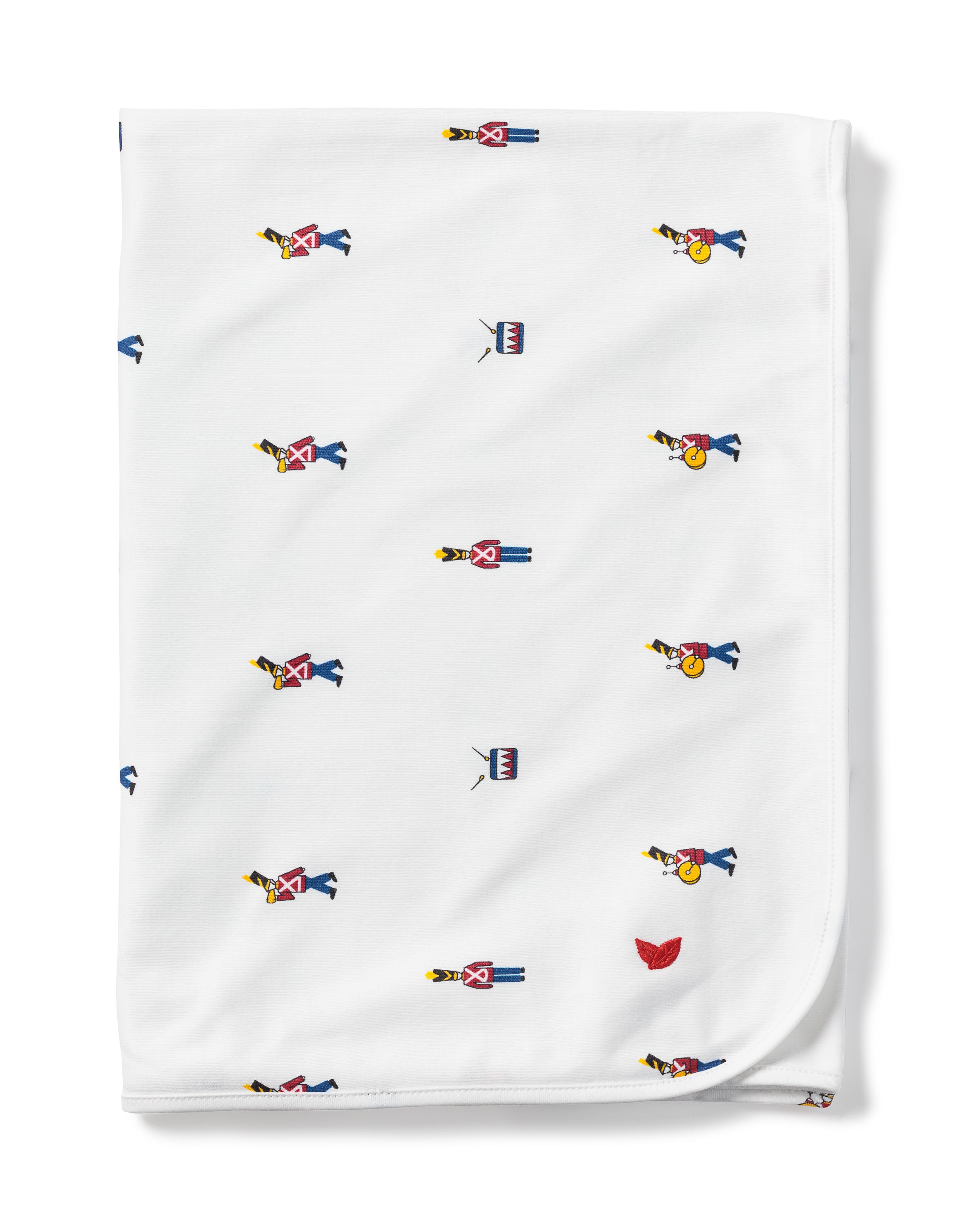 The Pima Baby Blanket in Toy Soldier by Petite Plume is crafted from luxurious Peruvian Pima Cotton, with small prints of toy soldiers in red and blue uniforms, complete with hats and rifles. A charming red leaf design is scattered on the fabric at one corner.