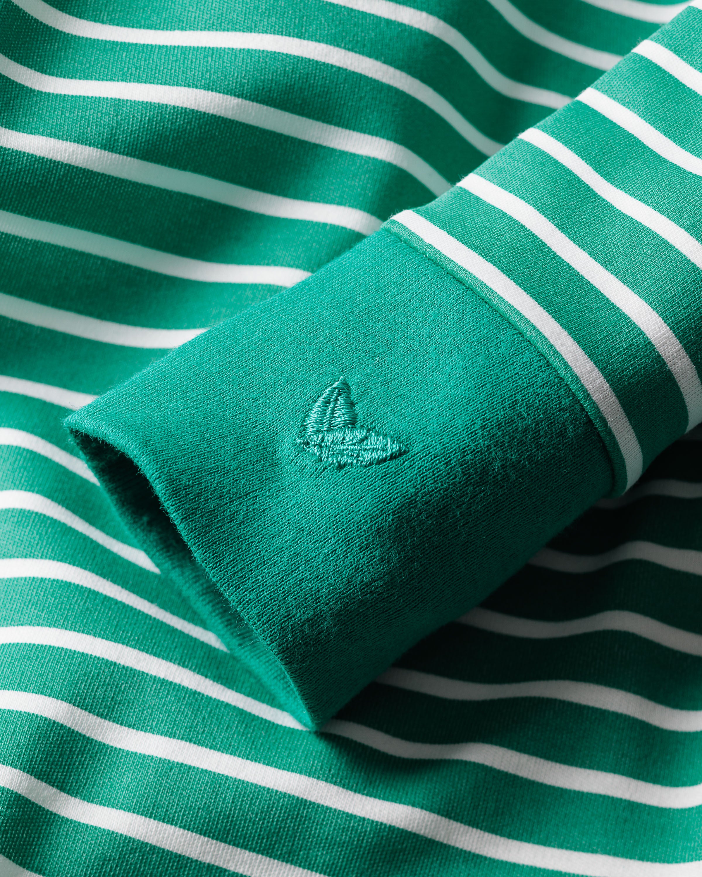 Close-up of a luxuriously crafted Babys Pima Romper in Green Stripe by Petite Plume, featuring a green and white stripe design with an embroidered tree on the sleeve, perfect for elegant daywear.