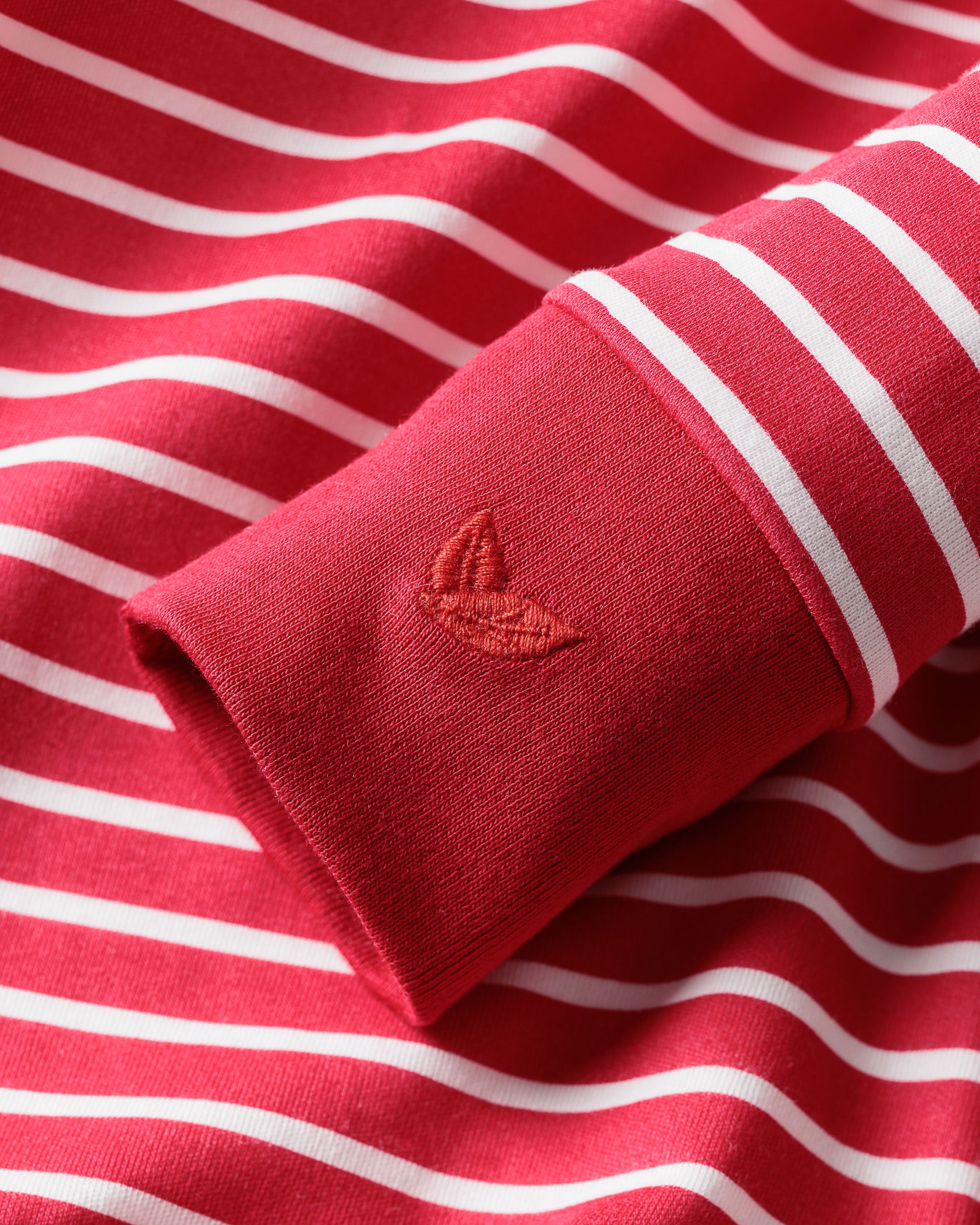 Close-up of the Babys Pima Romper in Red Stripe by Petite Plume, featuring a stylized leaf embroidery on the sleeve with elegant red and white horizontal stripes.