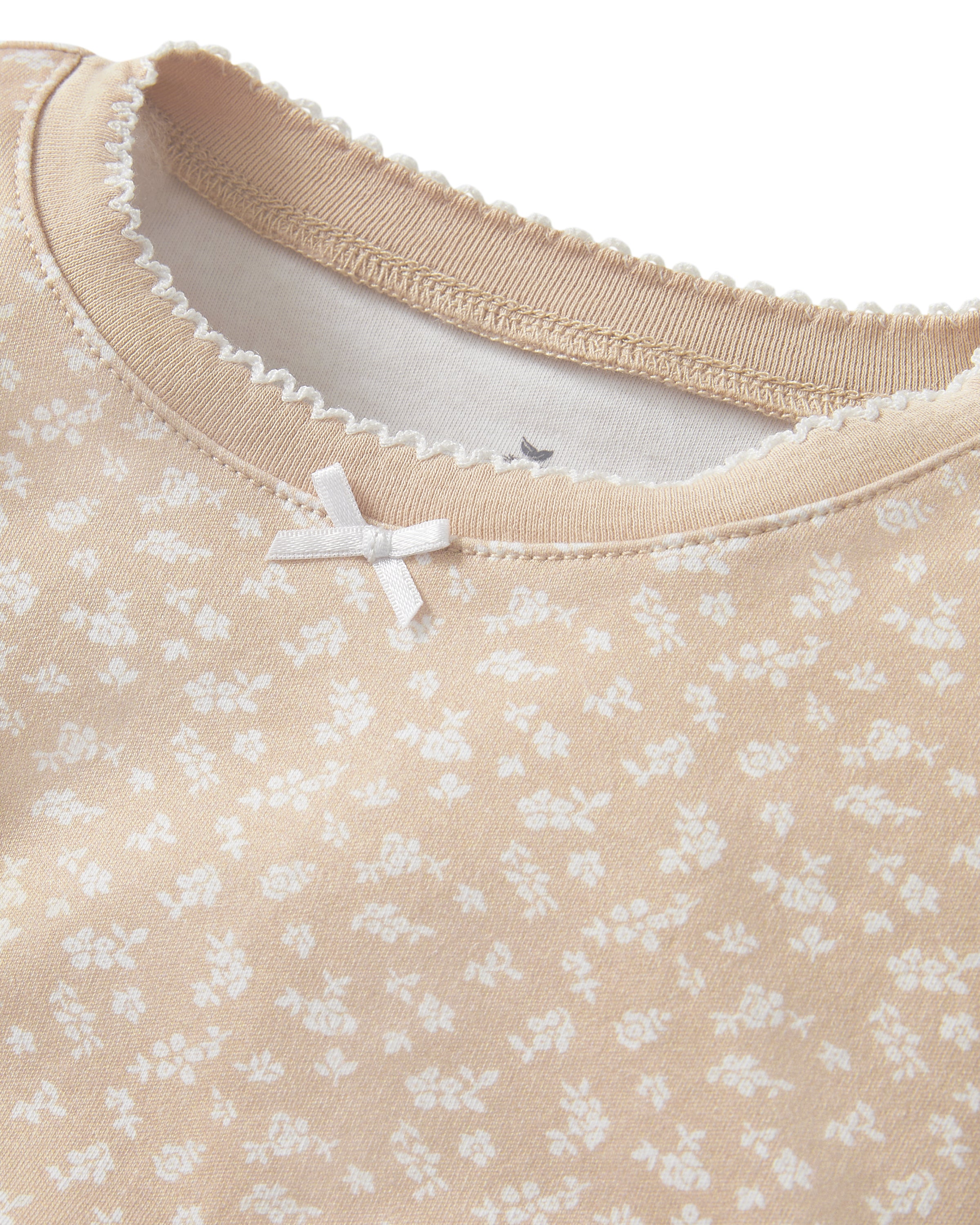 The Kid's Pima Snug Fit Pajama Set in Ditsy Waltz Camel features a beige long-sleeve top and matching pants with a white floral pattern and solid beige cuffs on the sleeves, neckline, and pant legs.