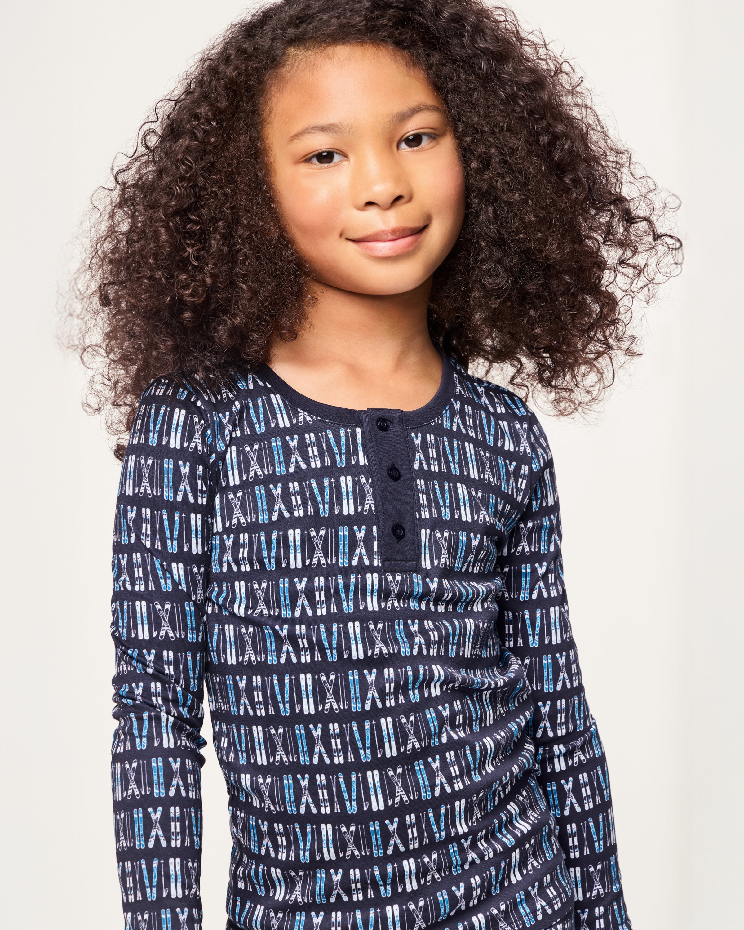 The Kid's Pima Snug Fit Pajama Set in Ski Trails features a coordinated long-sleeve top and pants with a blue and black geometric design and dark blue cuffs on the sleeves, neckline, and pant legs.