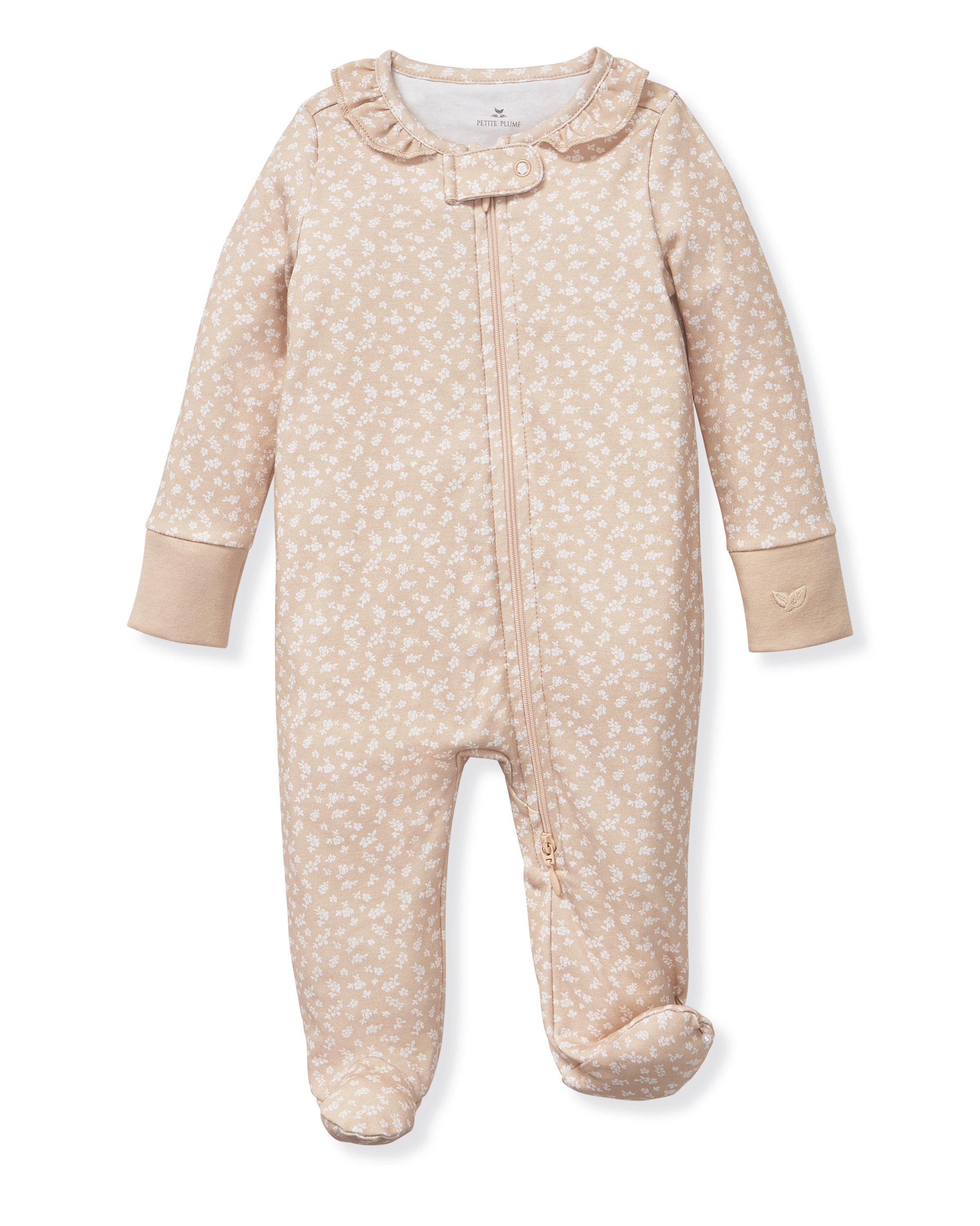 The Baby's Pima Romper in Ditsy Waltz Camel features a beige color with a white floral pattern, long sleeves, covered feet, fold-over cuffs, a ruffled collar, and a diagonal zipper closure.