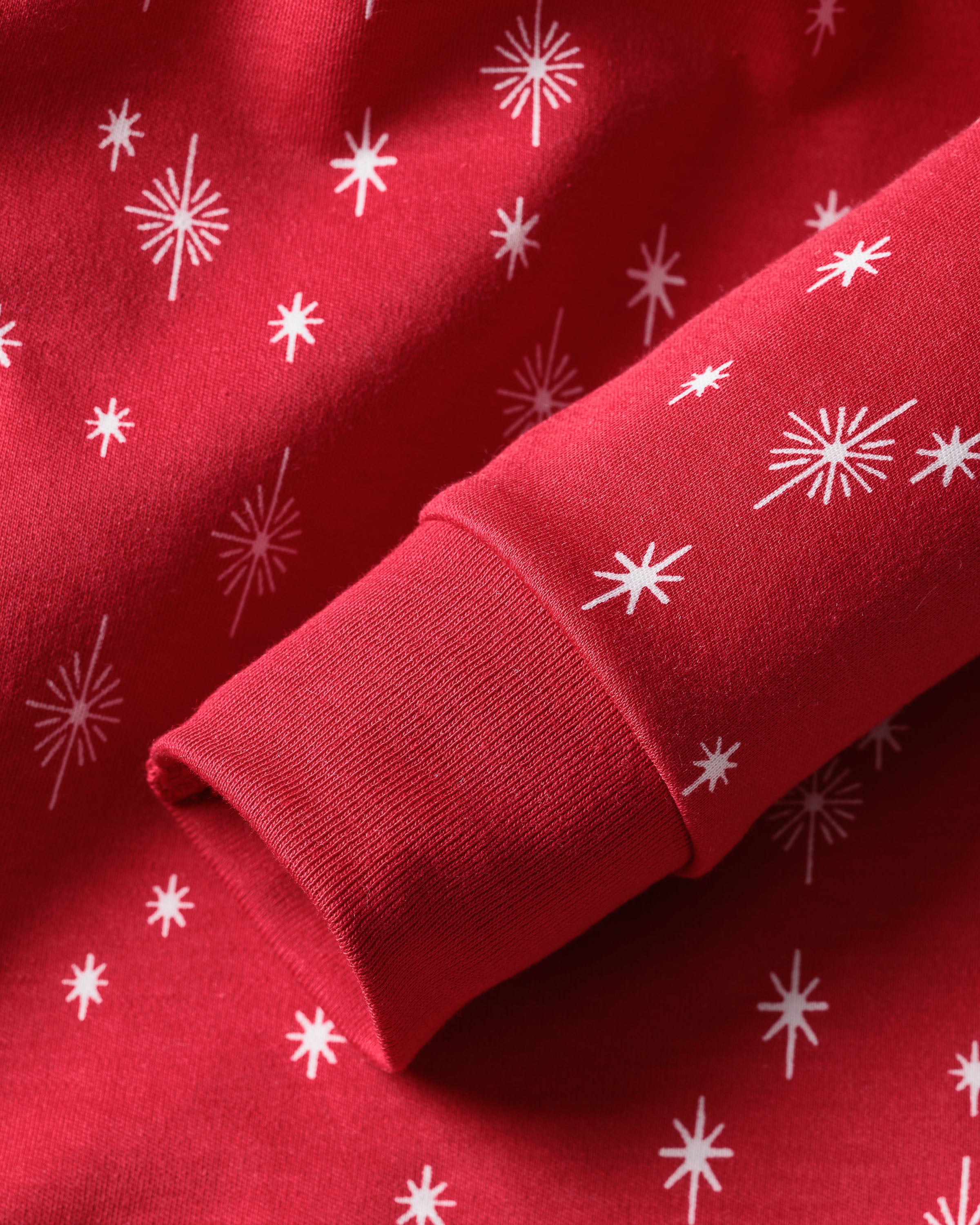The Petite Plume Kids Pima Snug Fit Pajama Set in Starry Night features a red long sleeve top with white star-shaped patterns in varying sizes, evenly spread across the soft Pima cotton fabric, creating a festive look ideal for cozy sleepwear.