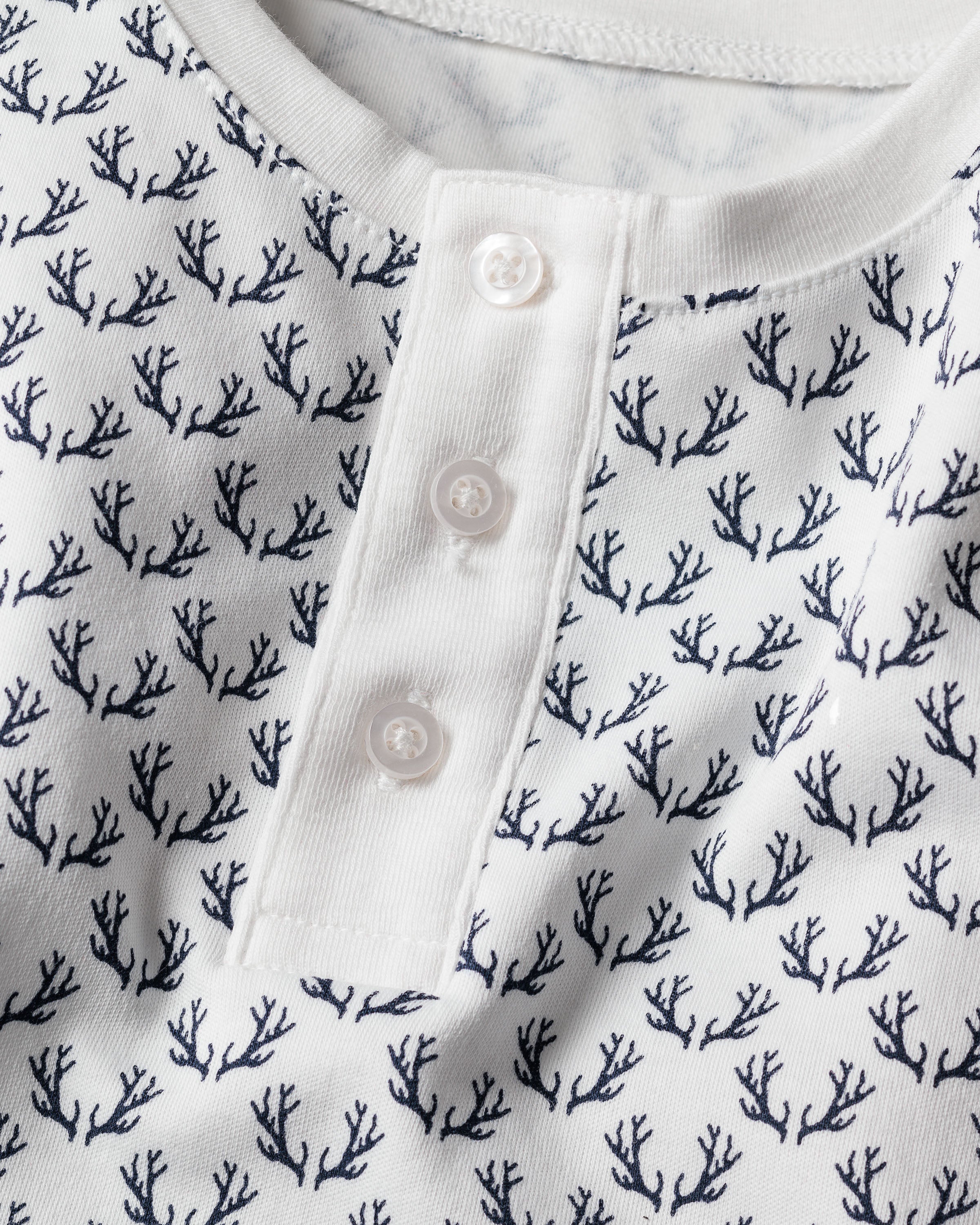 Close-up of Petite Plume’s Kids Pima Snug Fit Pajama Set in Nordic Antlers on White, featuring a soft texture and button-up placket with three white buttons. This long sleeve top, perfect for sleepwear, offers a casual yet elegant appearance.