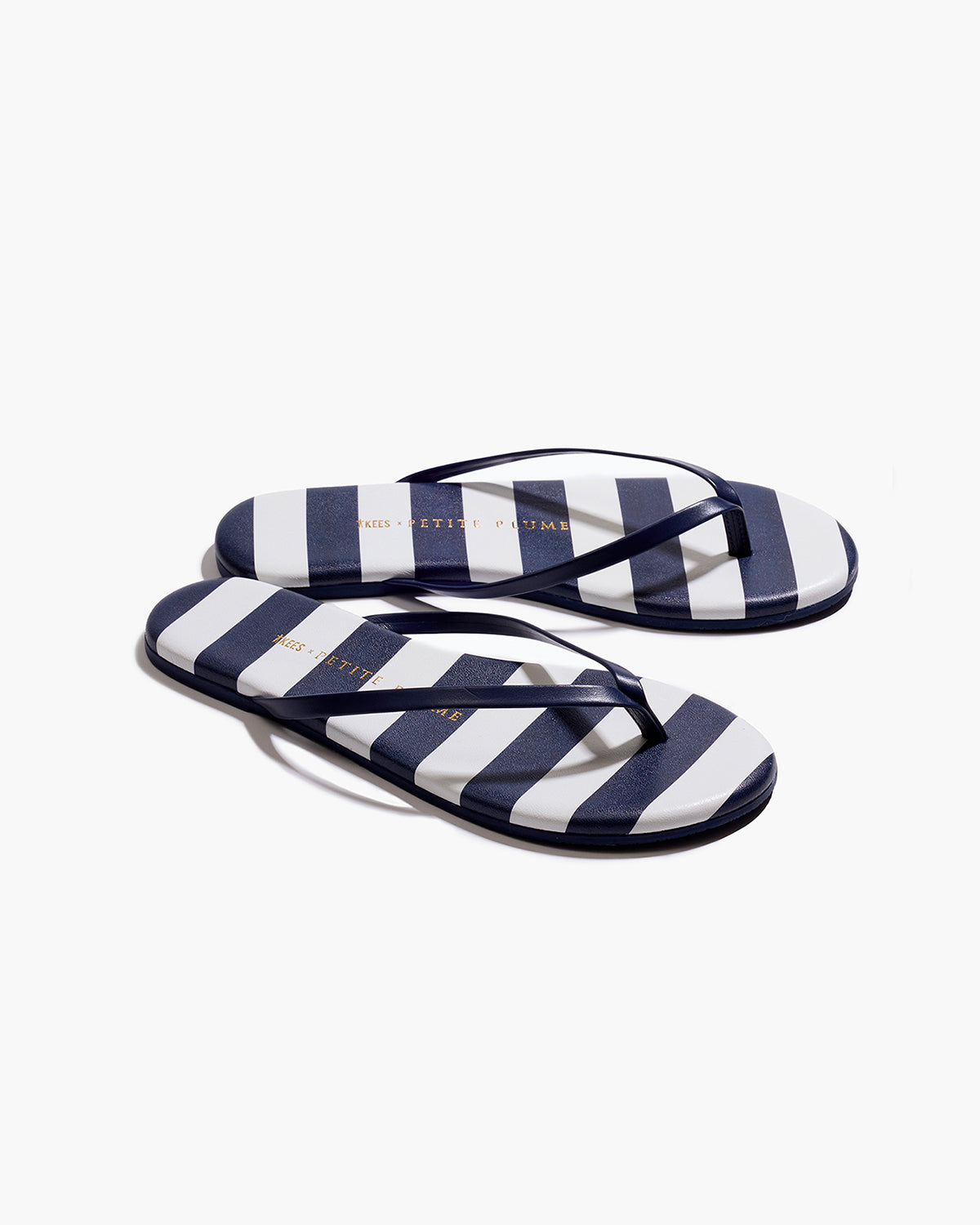 The Petite Plume x TKEES Lily Sandal in Cabana Stripe features navy blue and white horizontal stripes on the footbed with navy straps, shown side by side on a white background.
