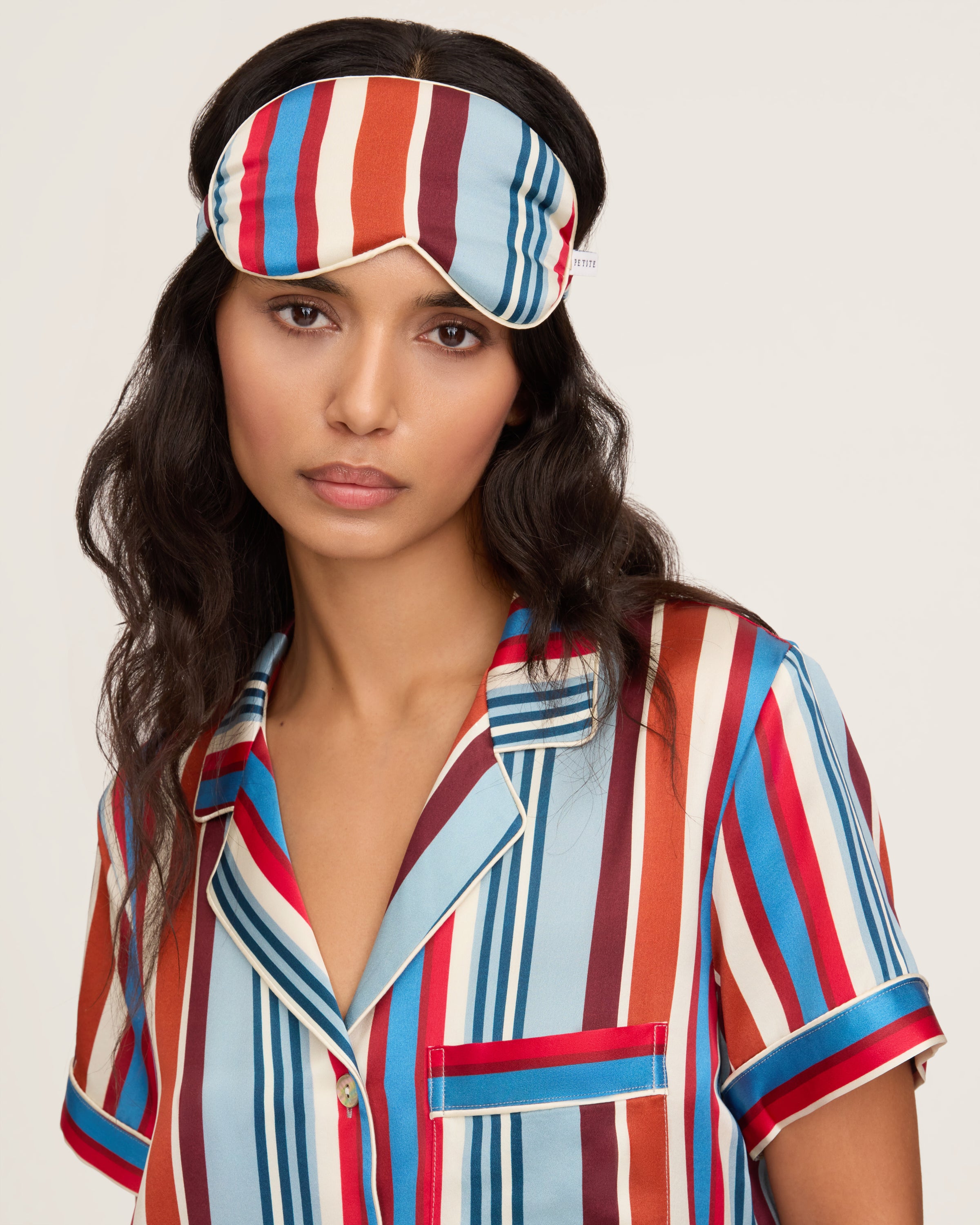 The Silk Eye Mask in Discovery Stripe features bold vertical blue, red, and white stripes, an elastic strap, and a small white label on the right side.
