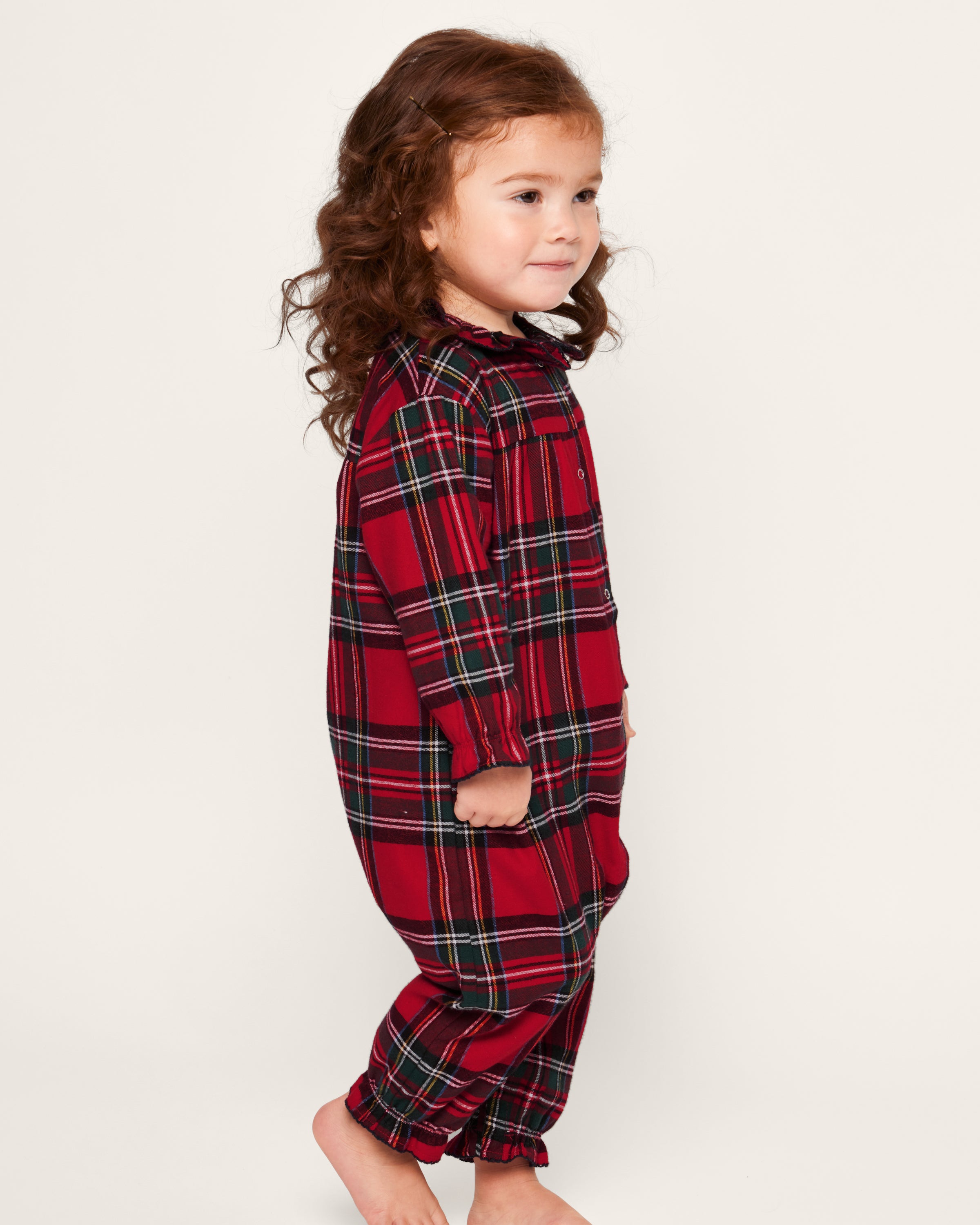 The Baby's Brushed Twill Madeline Romper in Imperial Tartan features long sleeves, a ruffled collar, snap buttons down the front, and gathered cuffs, all in a festive red, green, and white plaid.