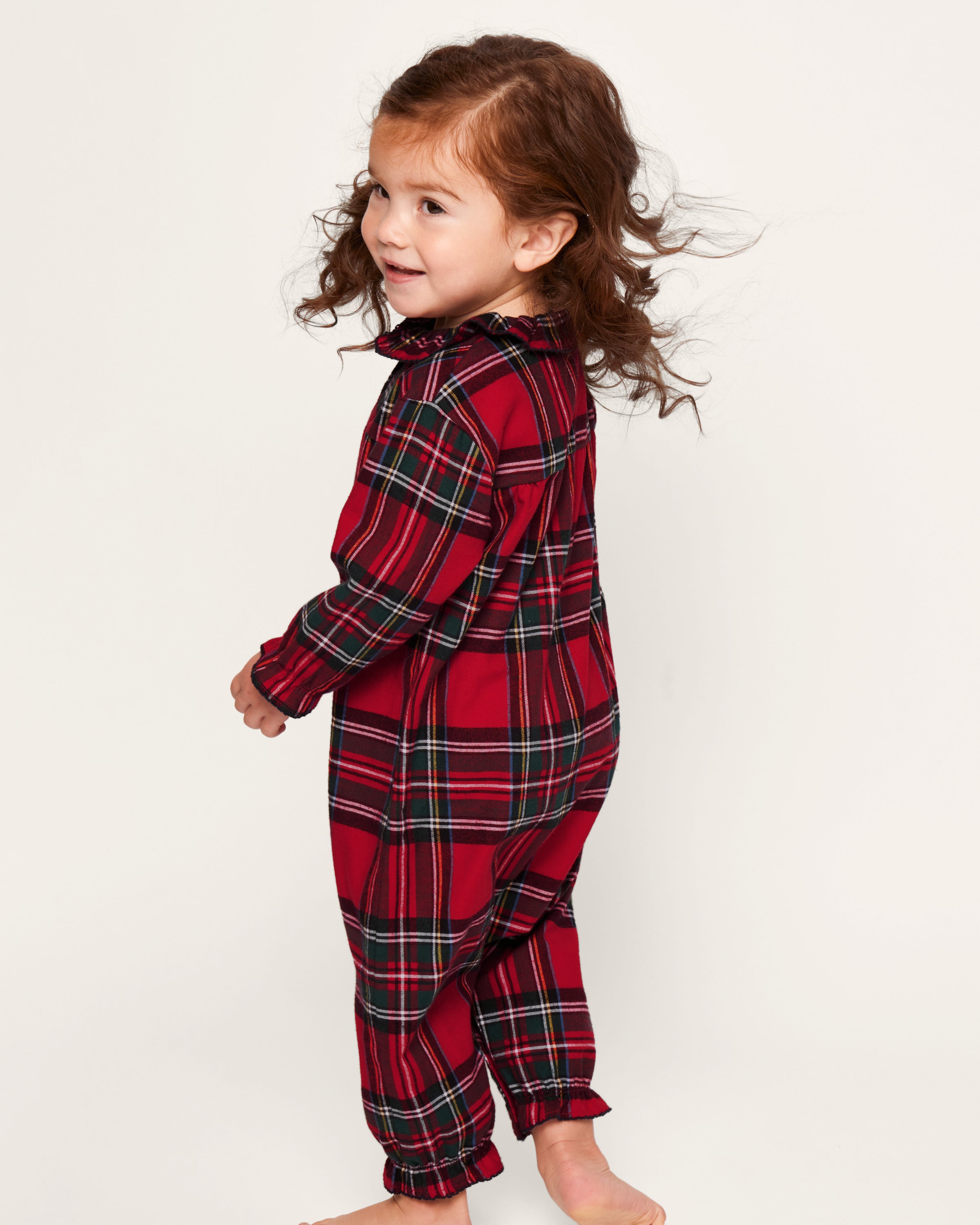 The Baby's Brushed Twill Madeline Romper in Imperial Tartan features long sleeves, a ruffled collar, snap buttons down the front, and gathered cuffs, all in a festive red, green, and white plaid.