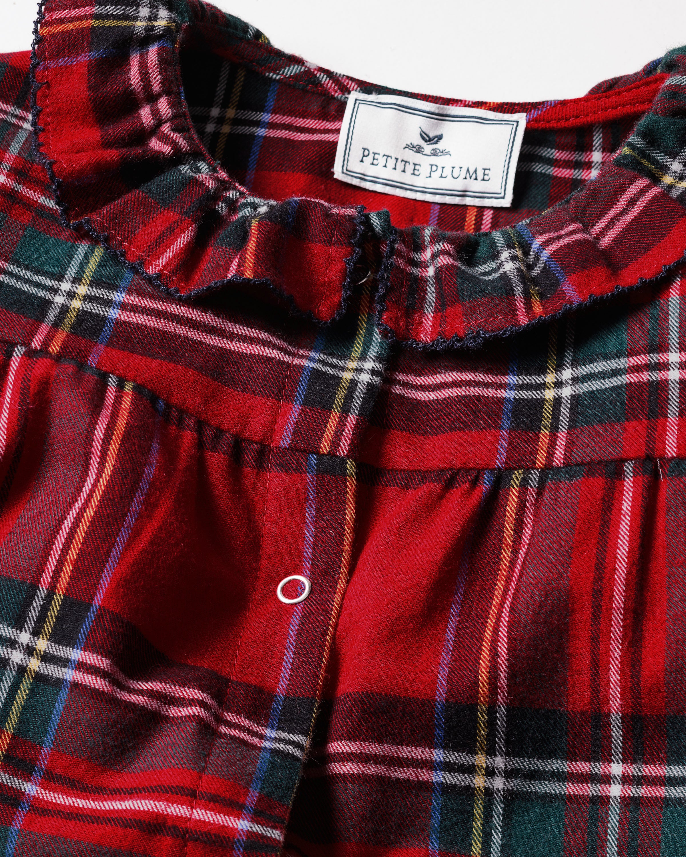 The Baby's Brushed Twill Madeline Romper in Imperial Tartan features long sleeves, a ruffled collar, snap buttons down the front, and gathered cuffs, all in a festive red, green, and white plaid.