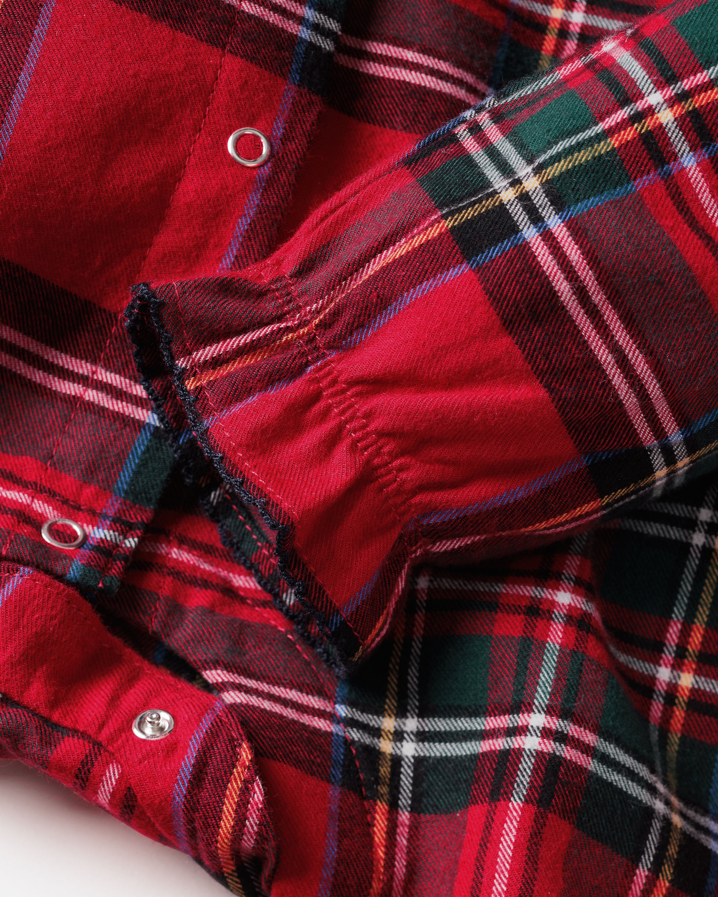 The Baby's Brushed Twill Madeline Romper in Imperial Tartan features long sleeves, a ruffled collar, snap buttons down the front, and gathered cuffs, all in a festive red, green, and white plaid.