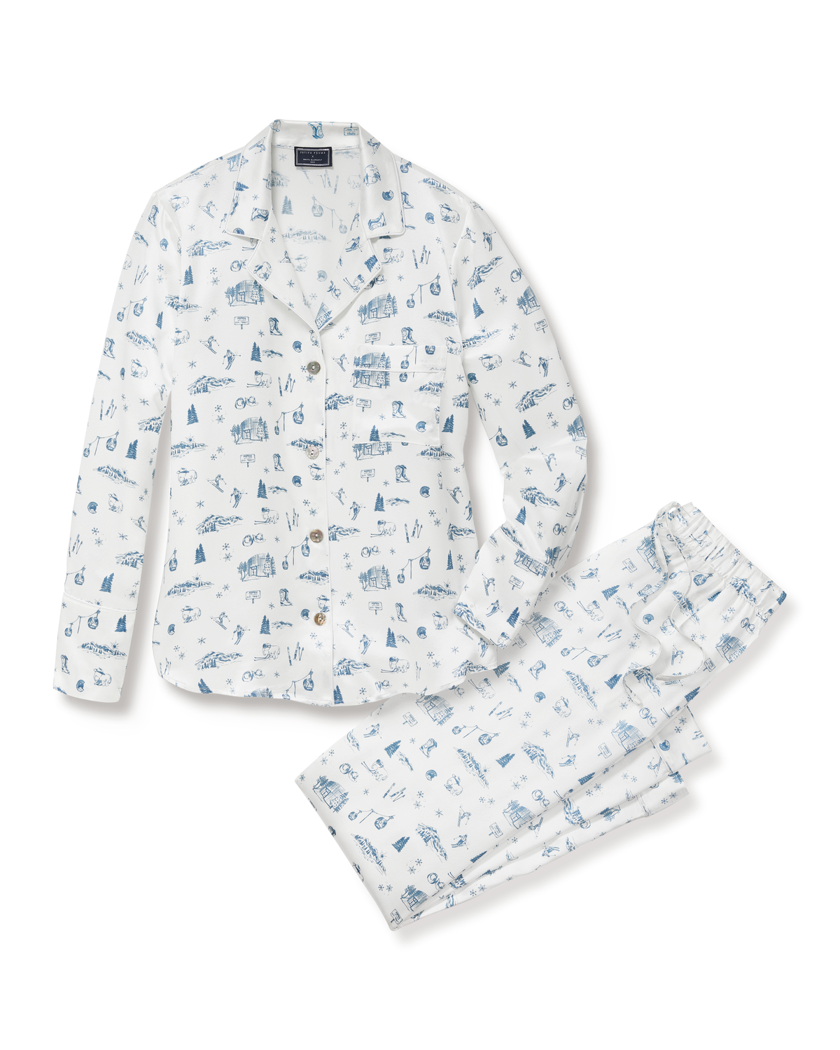 The Petite Plume x White Elephant Women’s Silk Pajama Set is shown laid flat on a white background. This set features a long-sleeve, button-up top and matching pants in white silk, adorned with blue hand-drawn illustrations.