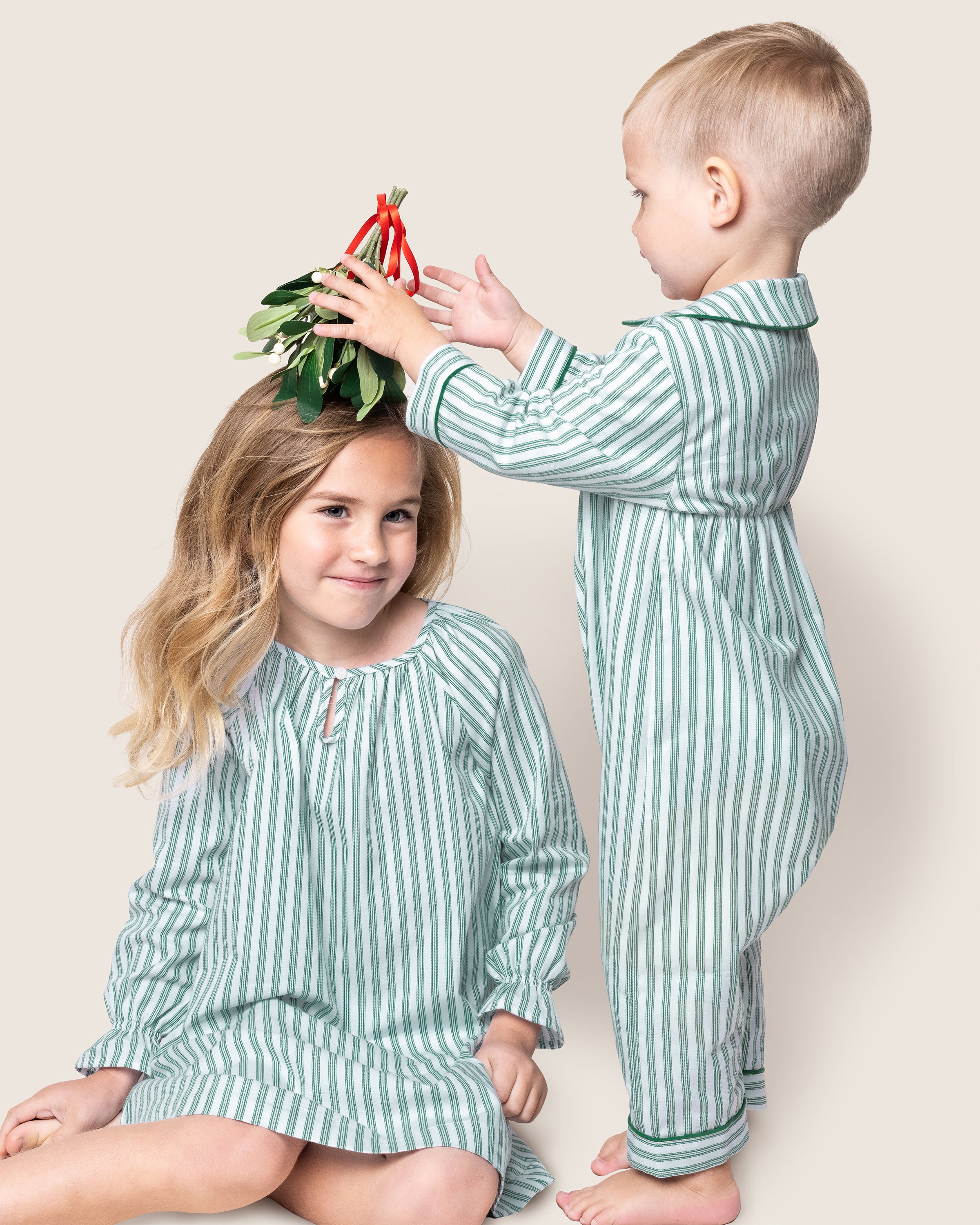 The Girl's Twill Delphine Nightgown in Emerald Ticking features vertical green and white stripes, long sleeves with ruffled cuffs, a gathered neckline, and a small bow detail at the center.