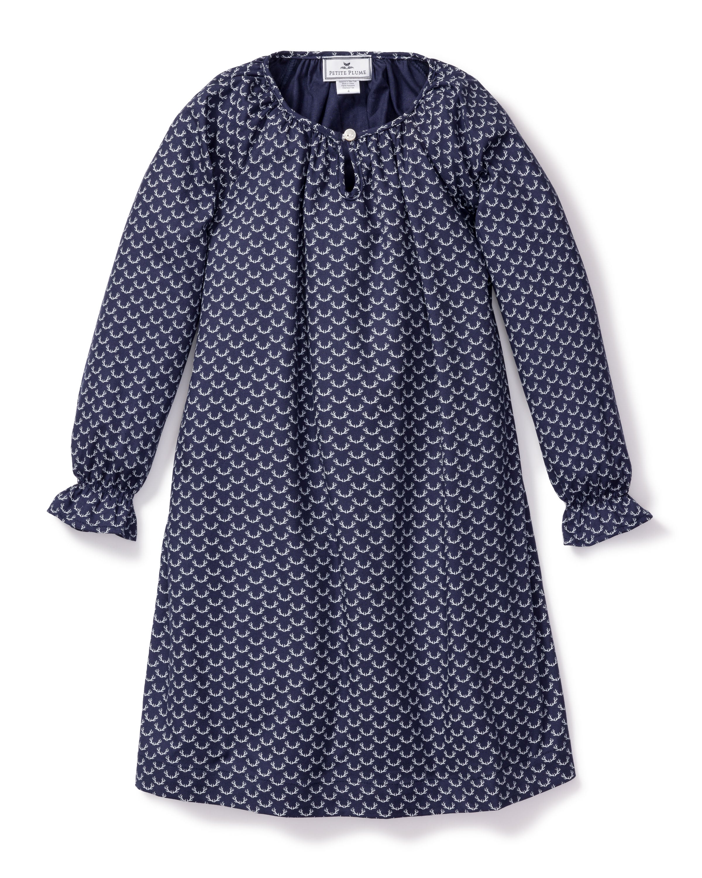 The Girls Twill Delphine Nightgown in Nordic Antlers by Petite Plume features long sleeves, a navy hue with a white scallop design, a round neckline, small front button closure, and gathered cuffs for comfort and style. Crafted from moisture-wicking twill.
