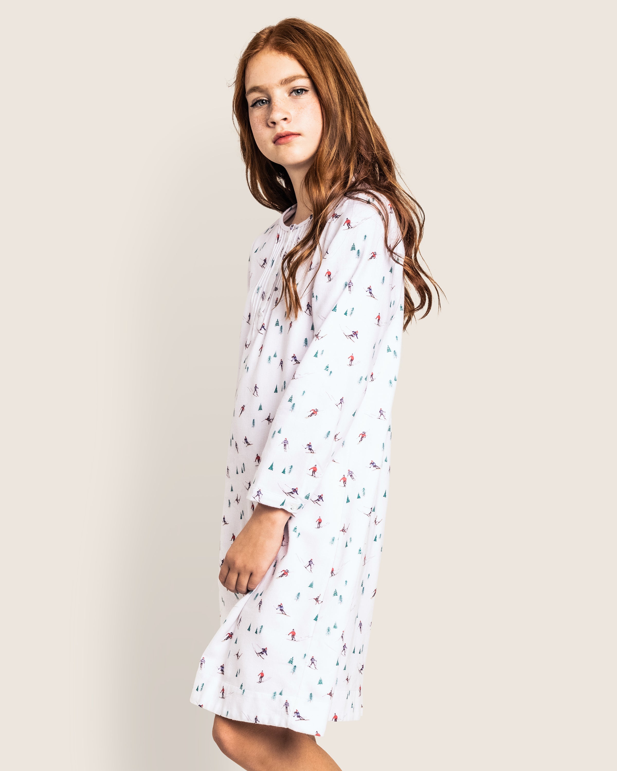 A young girl with long red hair wears the Petite Plume Girls Flannel Beatrice Nightgown in Après Ski, facing sideways towards the camera against a plain light background.