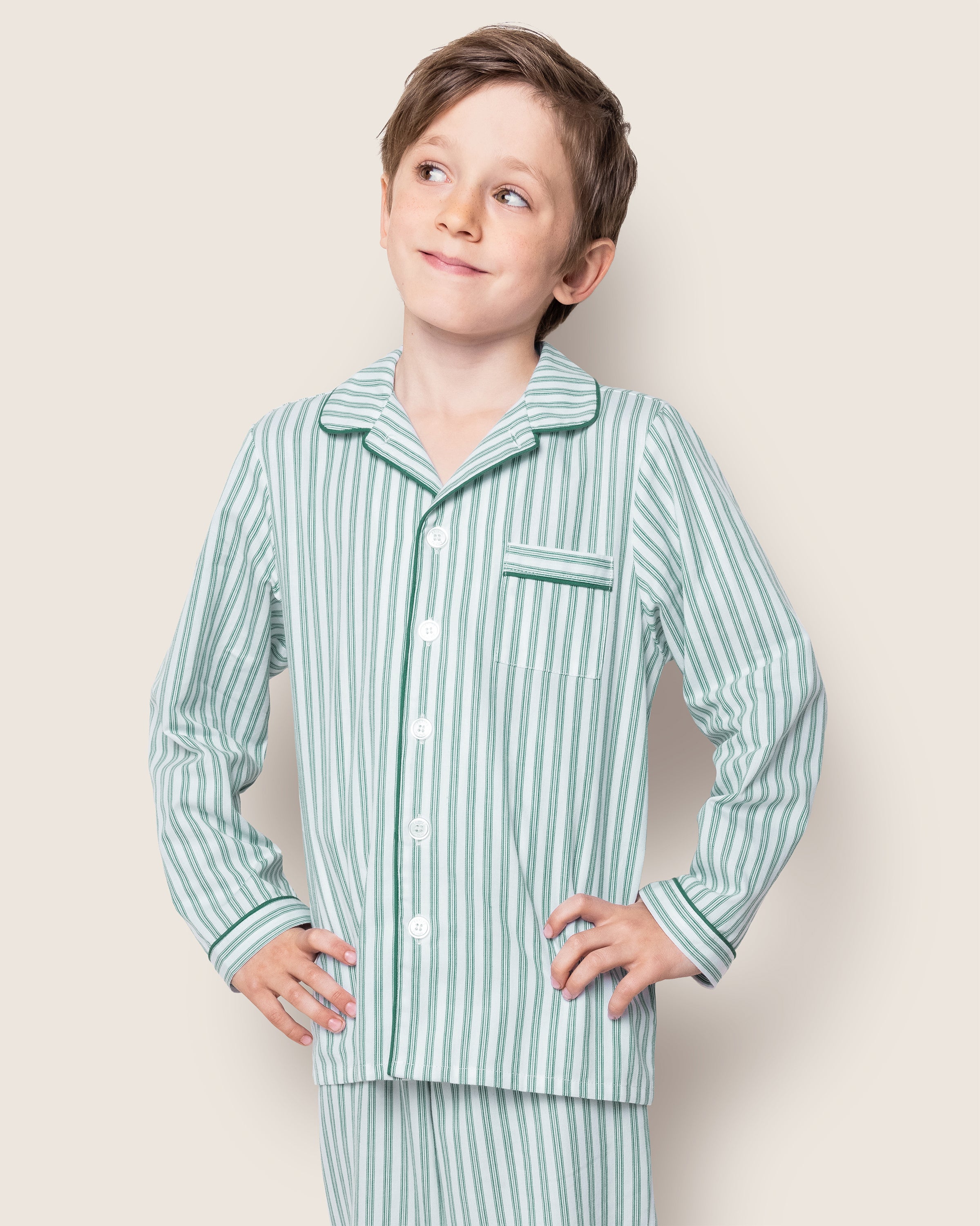 Close-up of Petite Plumes Kids Twill Pajama Set in Emerald Ticking, showcasing vertical blue and white stripes with green trim. The classic French ticking pattern includes buttons, a pocket, and visible cotton sleepwear texture and stitching details.