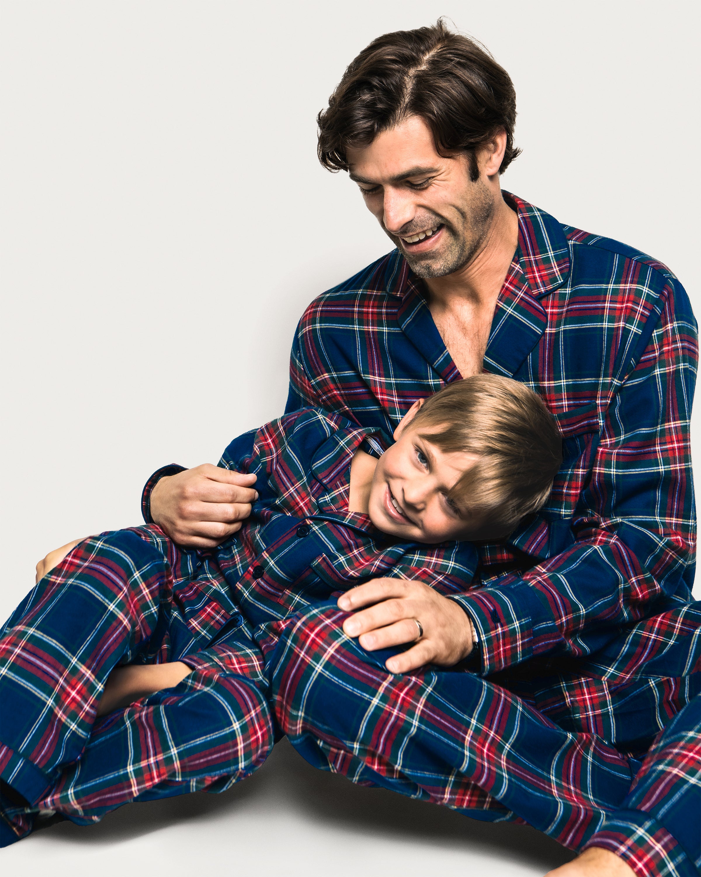 Close-up of a lavish Kids Brushed Cotton Pajama Set in Windsor Tartan by Petite Plume, showcasing red, blue, green, and yellow intersecting stripes forming squares and rectangles. A visible button and seam complete this classic pajama look.