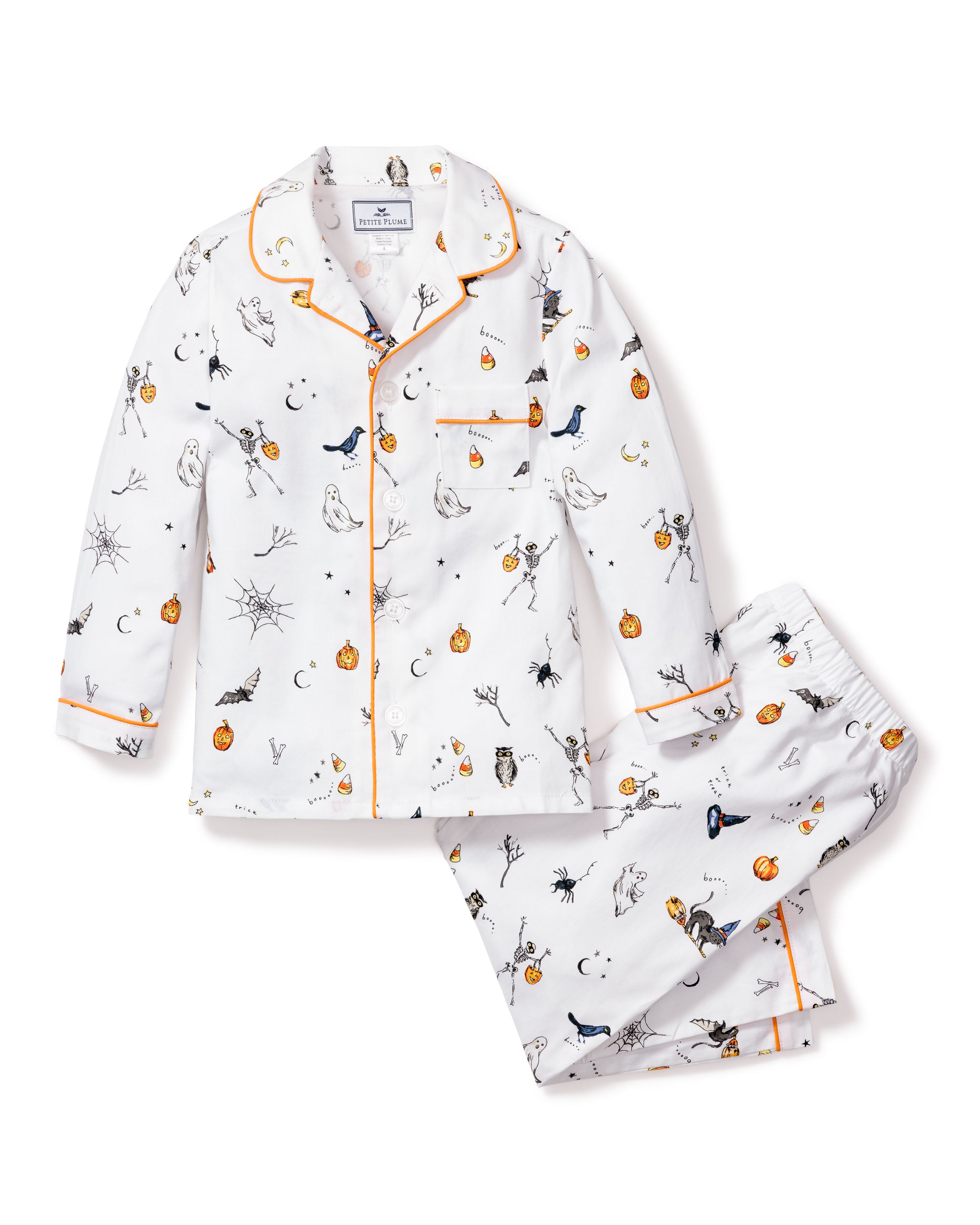 Petite Plumes Kids Twill Pajama Set in Trick or Treat features whimsical white pajamas adorned with Halloween-themed pumpkins, spiders, moons, and playful animals. This luxury sleepwear includes a button-up top with orange trim and matching pants in a festive print.