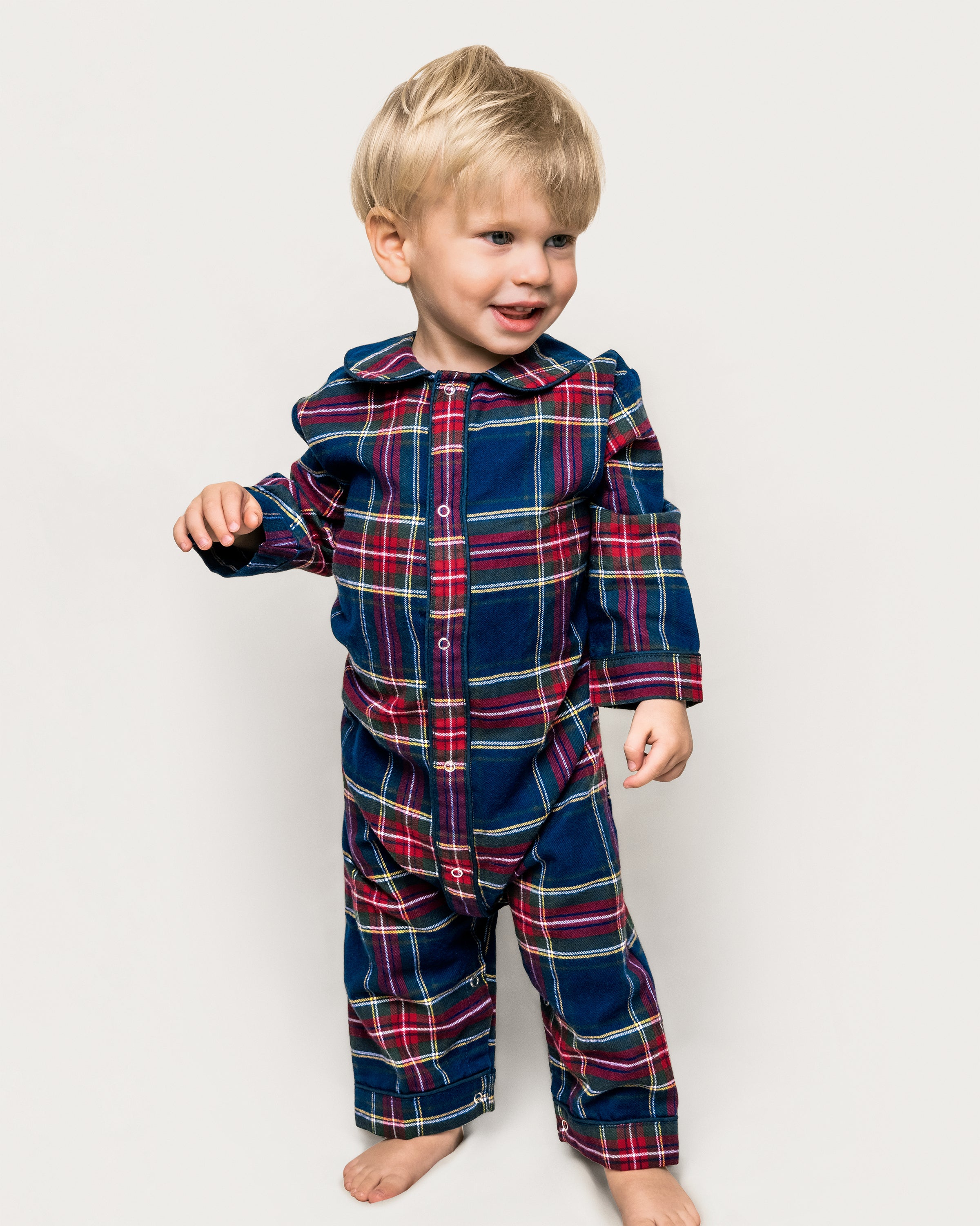 The Baby's Brushed Twill Cambridge Romper in Windsor Tartan features long sleeves and legs, a blue, red, and green plaid pattern, front snap buttons, and a rounded collar.