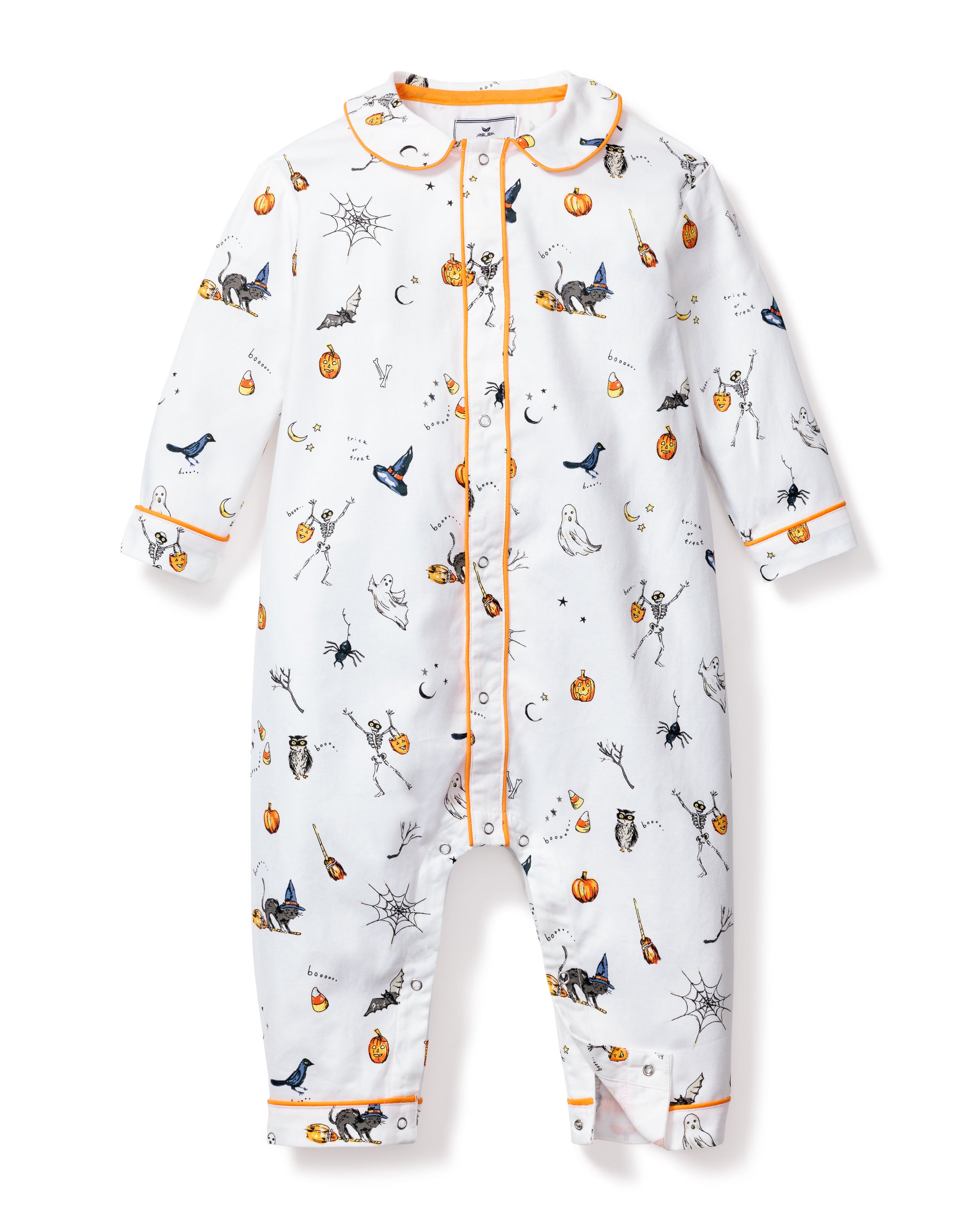 The Petite Plume Babys Twill Cambridge Romper in Trick or Treat is a white onesie featuring orange piping and Halloween icons such as pumpkins, ghosts, bats, skeletons, and cats. Made from flame retardant materials for safe nighttime adventures.