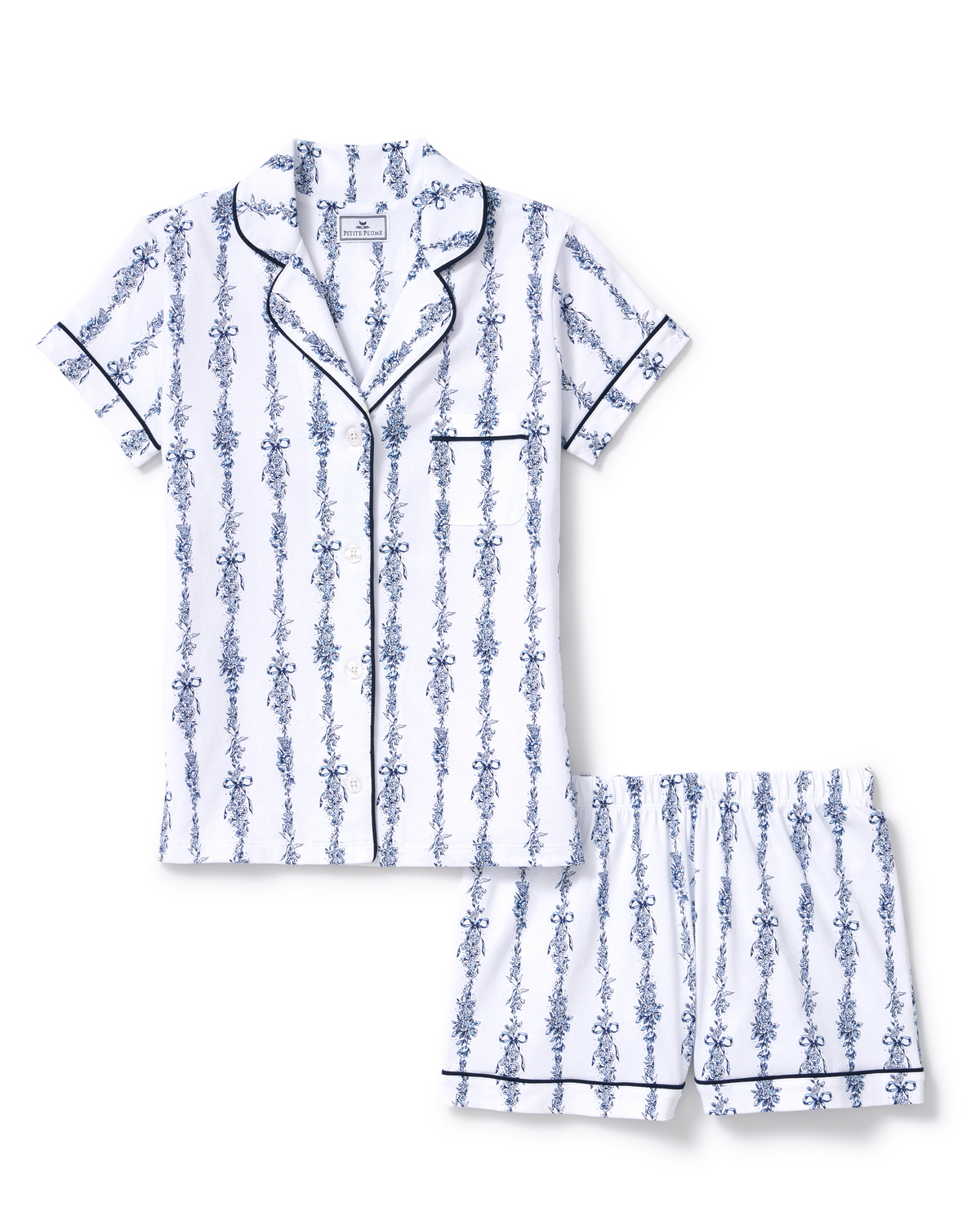 Greek Embroidered Poppy Pima Short Set in Navy Mayfair Toile features a white short-sleeve pajama top with a blue floral stripe pattern, detailed with navy piping along the collar, pocket, sleeves, and edges, paired with matching elastic-waist shorts.