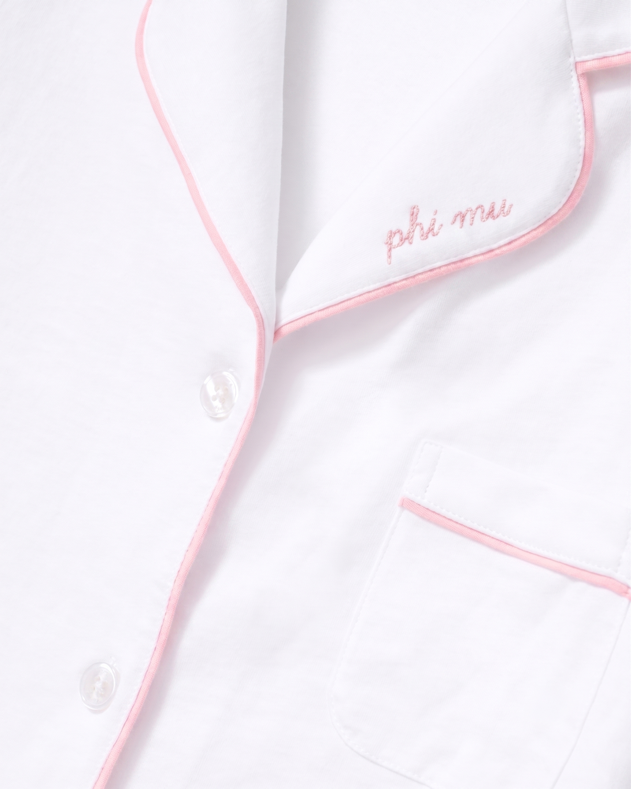 The Greek Embroidered Poppy Pima Short Set in White with Pink Piping features a white pajama shirt with pink piping trim, “Phi Mu” embroidered in pink script on the collar, a chest pocket, and white buttons.