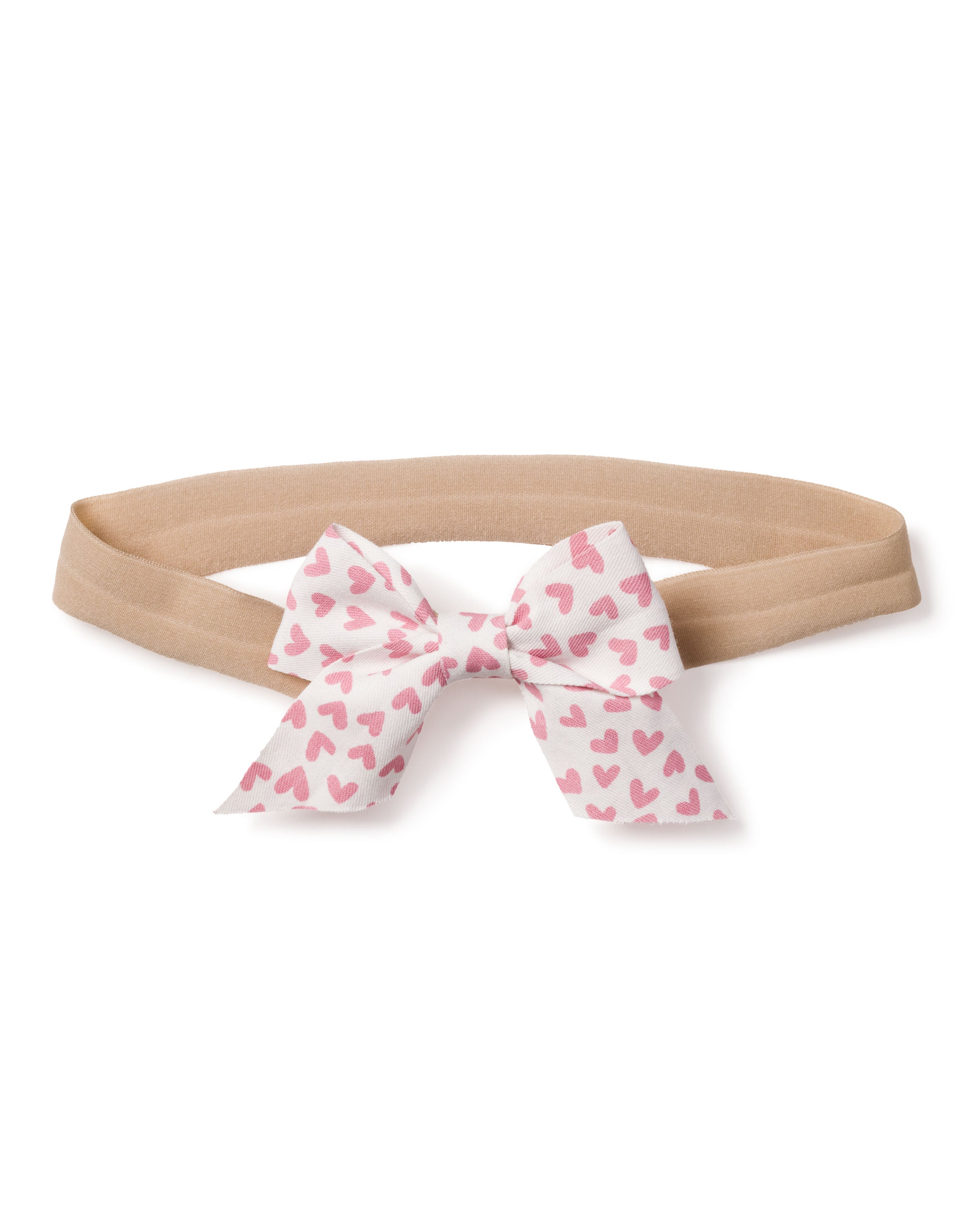 The Petite Plume Girls Hair Bow in Sweethearts features a beige headband with a white bow covered in pink hearts. Its playful design makes it ideal as a festive stocking stuffer or holiday gift. Perfect for adding charm to any girls outfit!.