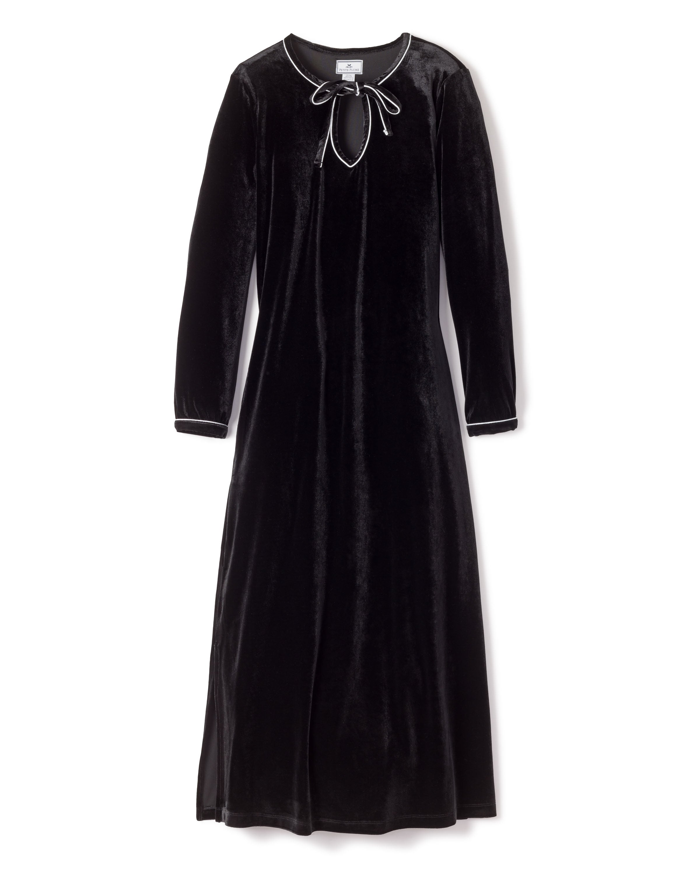 The Womens Velour Harlow Nightgown in Black by Petite Plume is a Hollywood-style dress from the Cabaret Collection. It features long sleeves, a round neckline, and white piping along the cuffs and neckline, finished with a bow tie detail at the front.