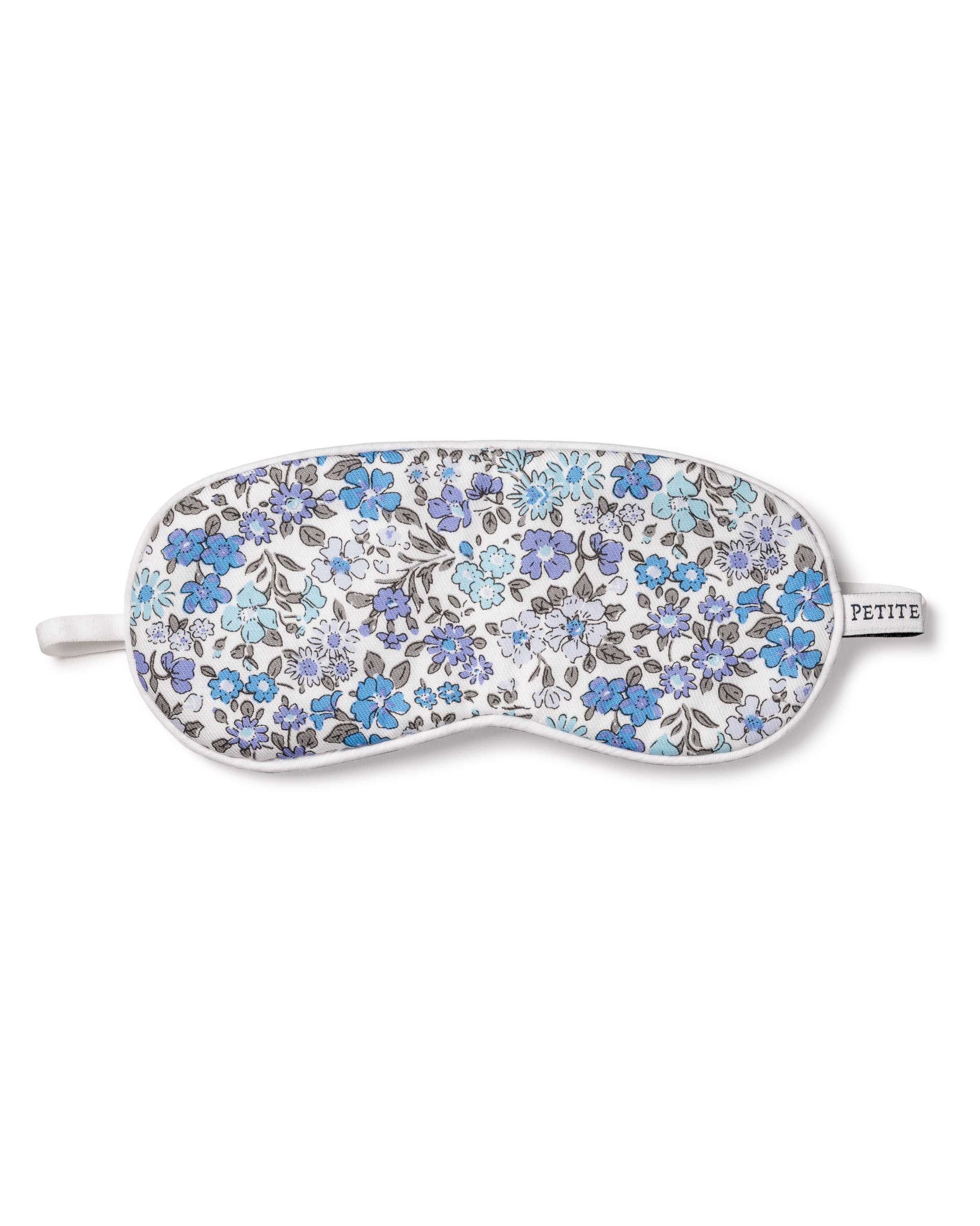 The Kids Twill Sleep Mask in Fleur DAzur by Petite Plume showcases a luxury floral pattern in blue, purple, and gray on white with a white strap and petite tag—ideal for pairing with matching masks or as an elegant monogrammed gift.