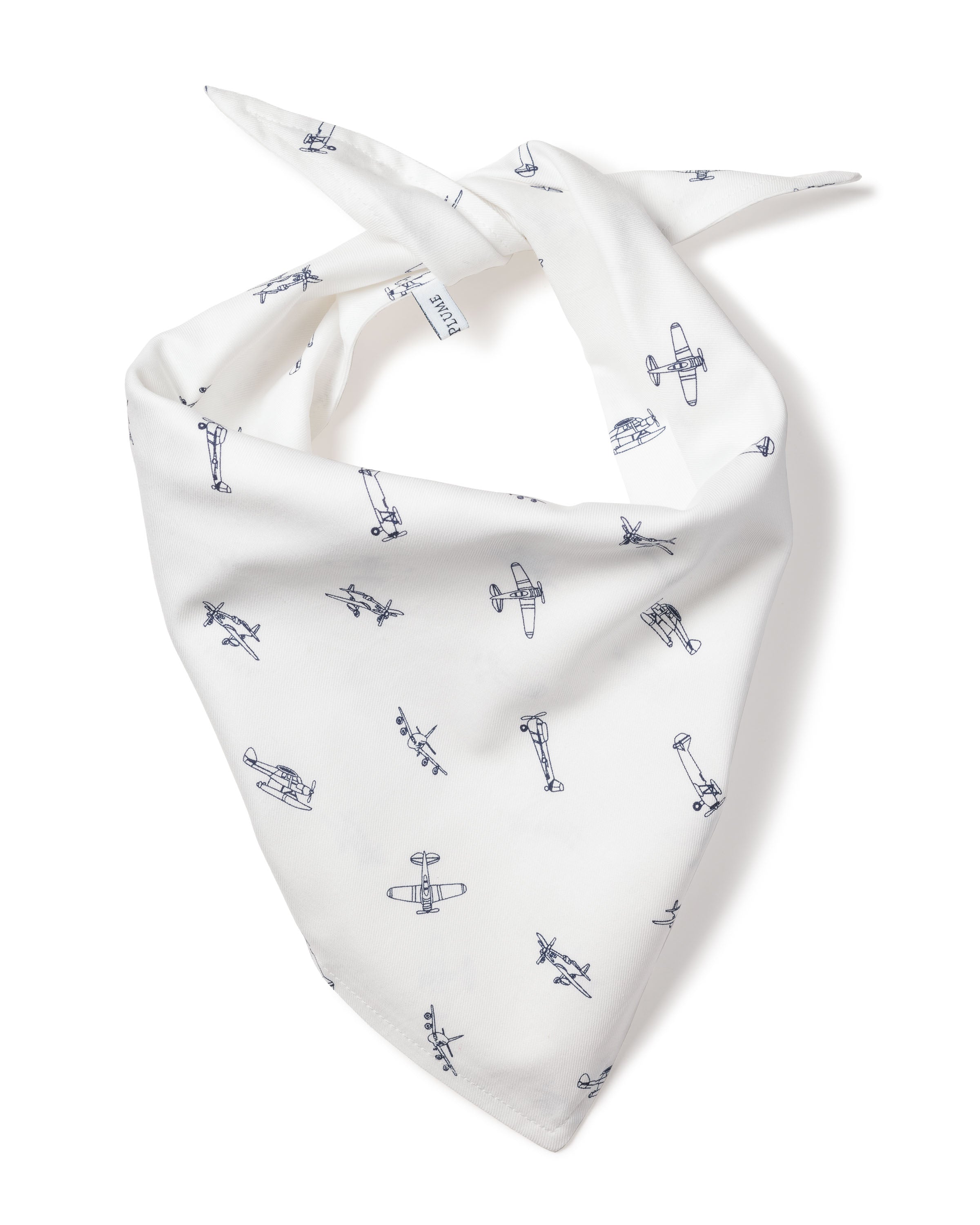 The Par Avion Dog Bandana by Petite Plume features a white fabric with black vintage airplane line drawings in a scattered pattern, tied at the top, creating a charming and perfect accessory for your dog.