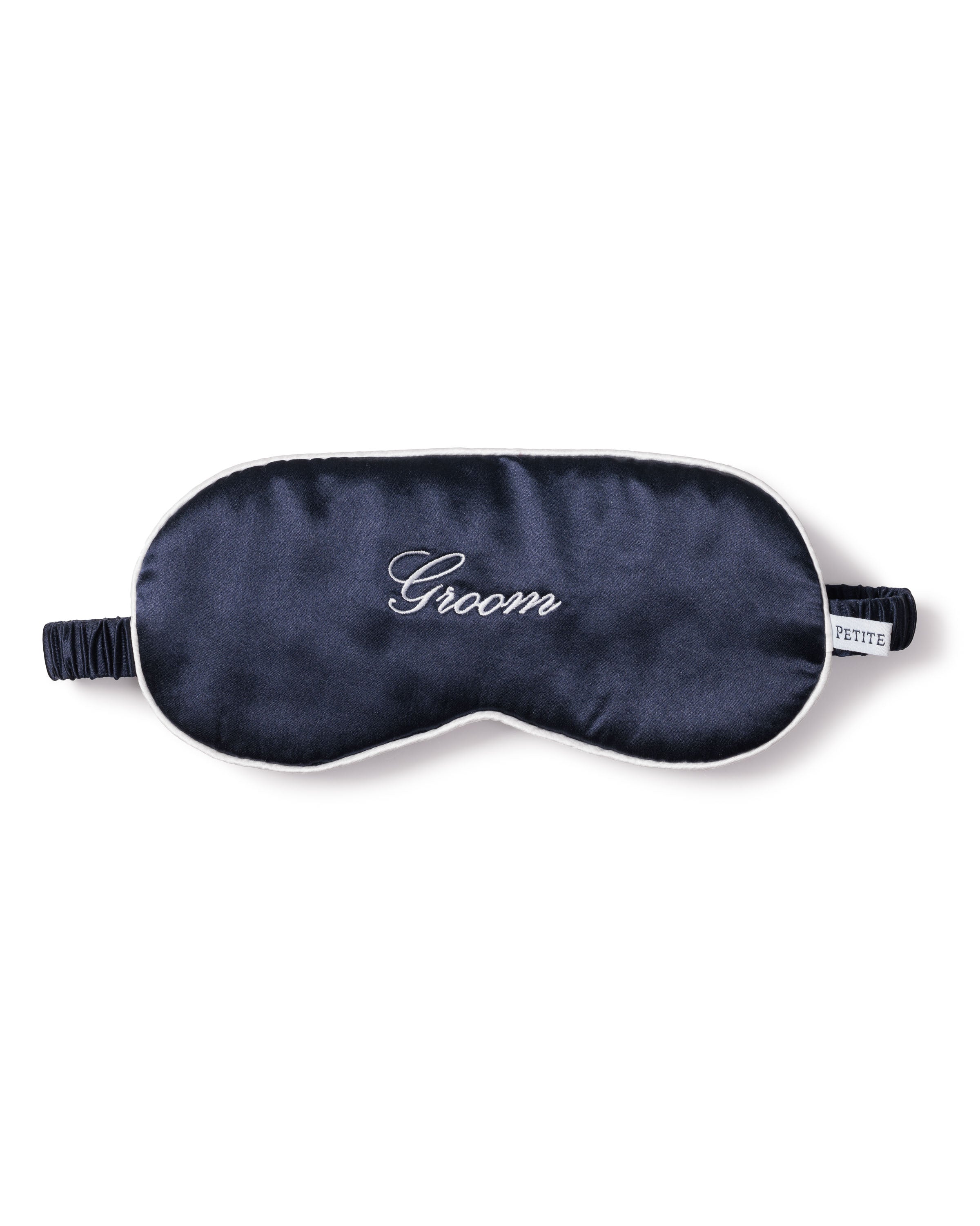 The Mens Silk Groom Sleep Mask in Navy by Petite Plume is crafted from luxurious mulberry silk with Groom embroidered in white cursive. Its perfect as a groom gift and features an adjustable strap and small side label.