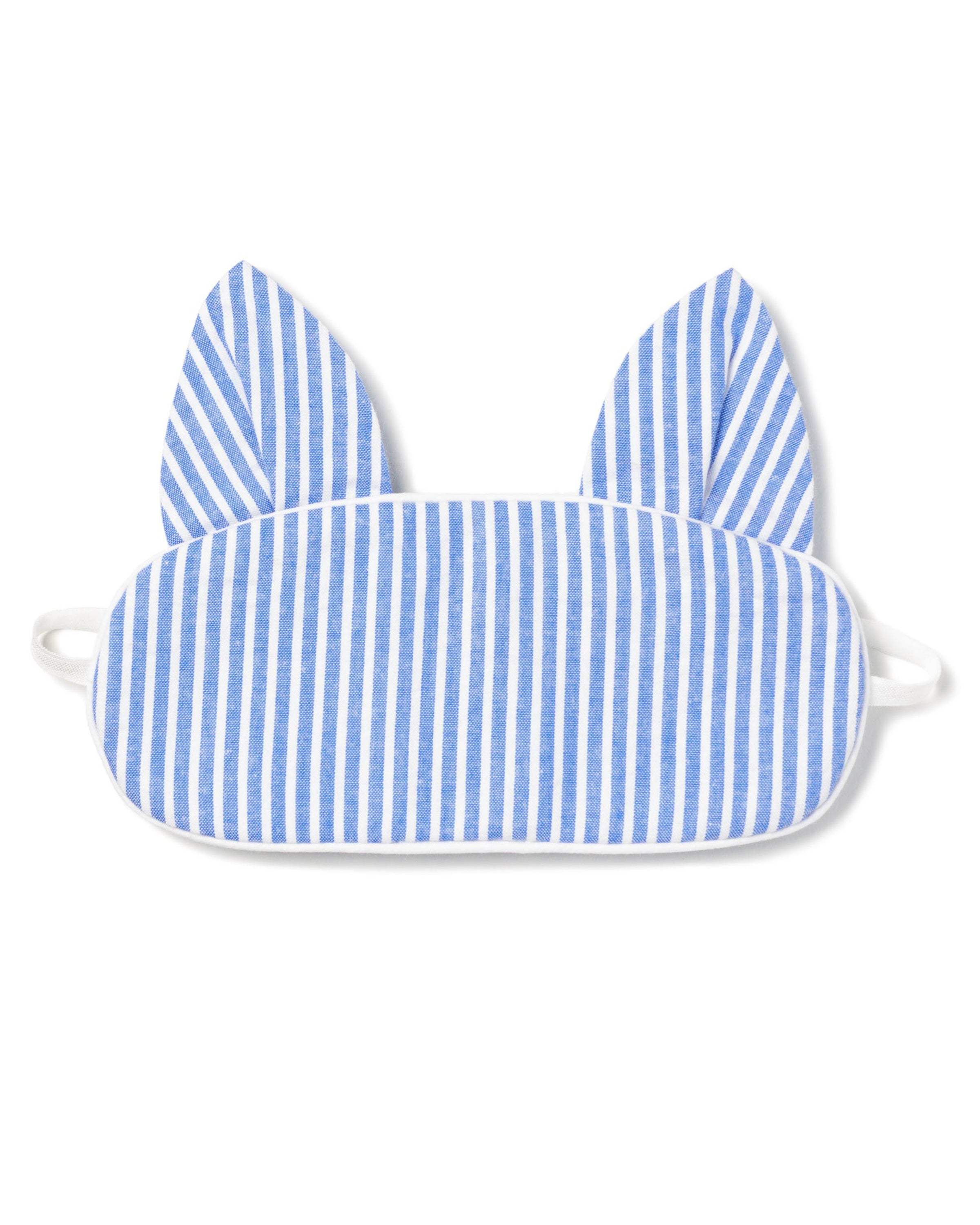 The Kids Kitty Sleep Mask in French Blue Seersucker by Petite Plume features cat-like ears and elastic straps for a snug fit. This playful mask can be monogrammed, making it an ideal gift. Consider matching masks for friends to share the cozy charm.