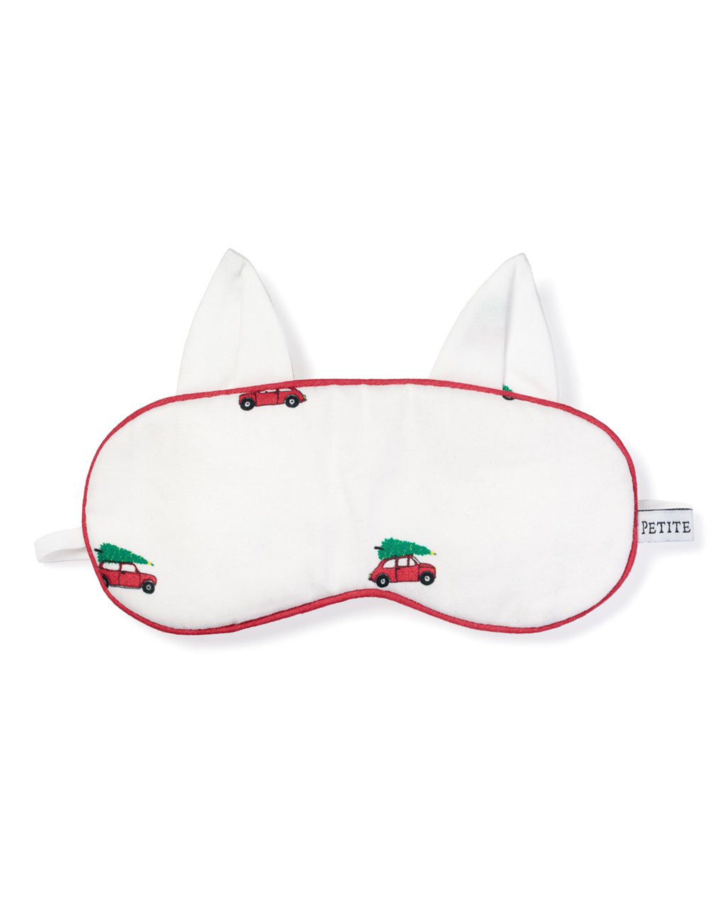 The Kids Twill Kitty Sleep Mask in Holiday Journey by Petite Plume features a whimsical design with red cars carrying Christmas trees, ear-like extensions, and festive red trim. A PETITE tag on the side adds charm, making it an ideal holiday gift for your sleepwear collection.