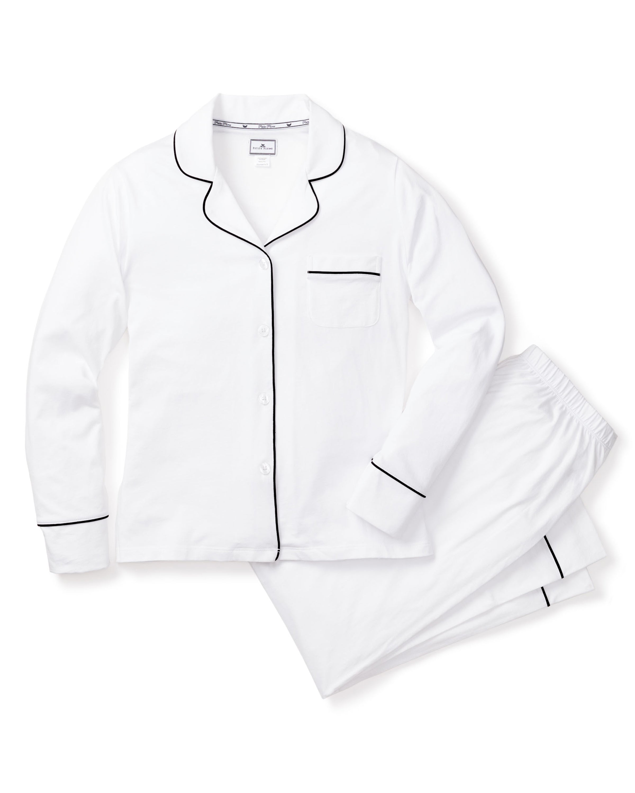 The Petite Plume Womens Pima Pajama Set in White with Black Piping includes a luxury sleepwear set made of soft Peruvian Pima cotton, featuring a long-sleeved, button-up shirt with black piping and chest pocket, and matching pants with black-piped cuffs.