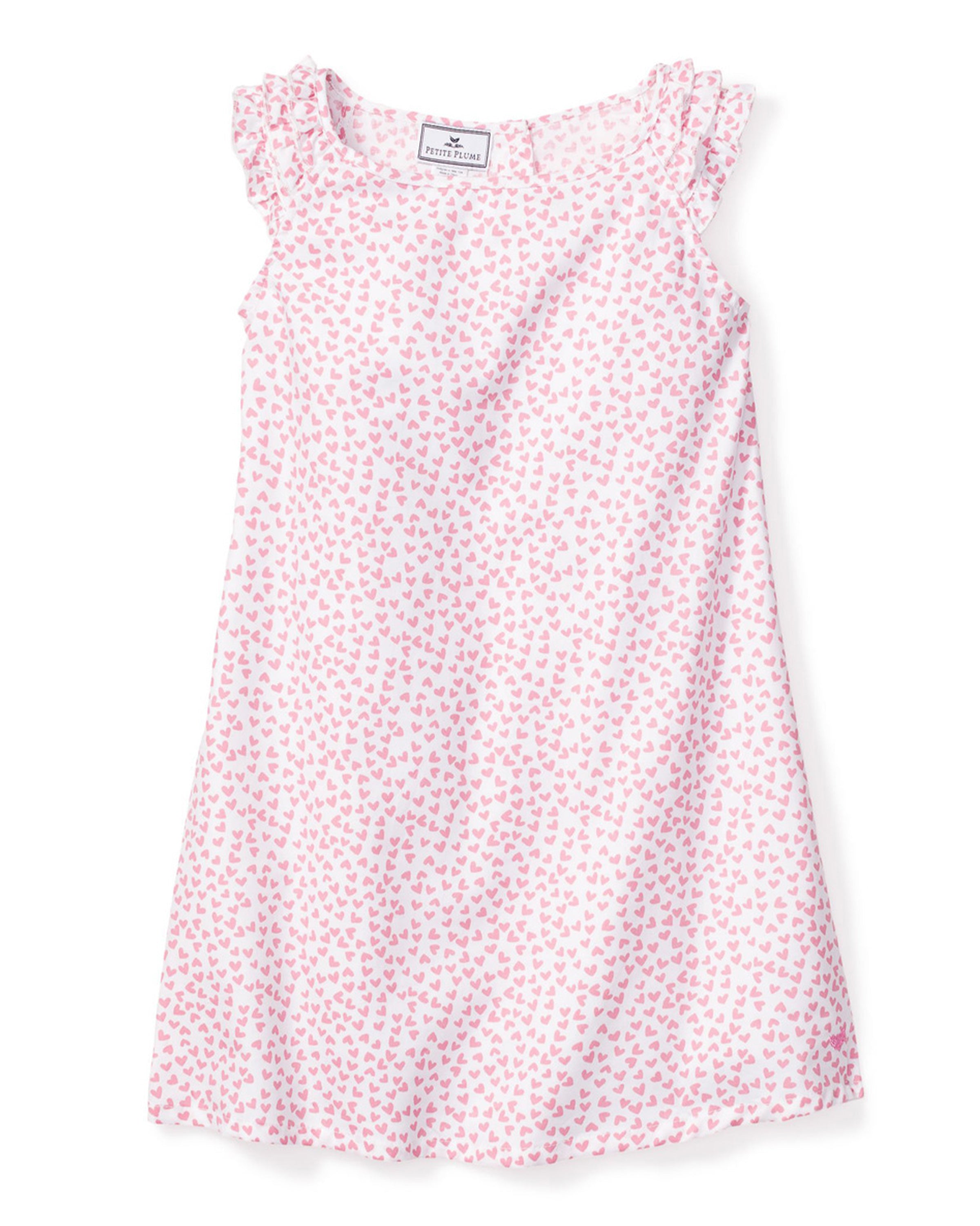 The Petite Plume Girls Twill Amelie Nightgown in Sweethearts, sleeveless with small pink hearts and ruffled shoulders, crafted from lightweight woven cotton, hangs gracefully.