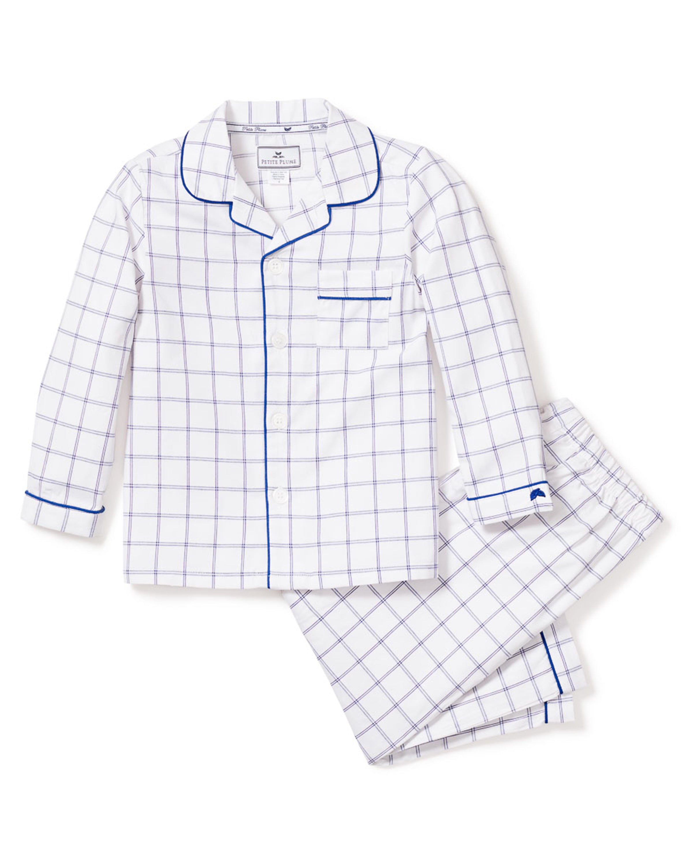 The Kids Twill Pajama Set in Nantucket Tattersall by Petite Plume features a blue checkered pattern on yarn-dyed cotton, complete with a long-sleeved button-up top with blue piping, a convenient breast pocket, and matching pants for stylish comfort.