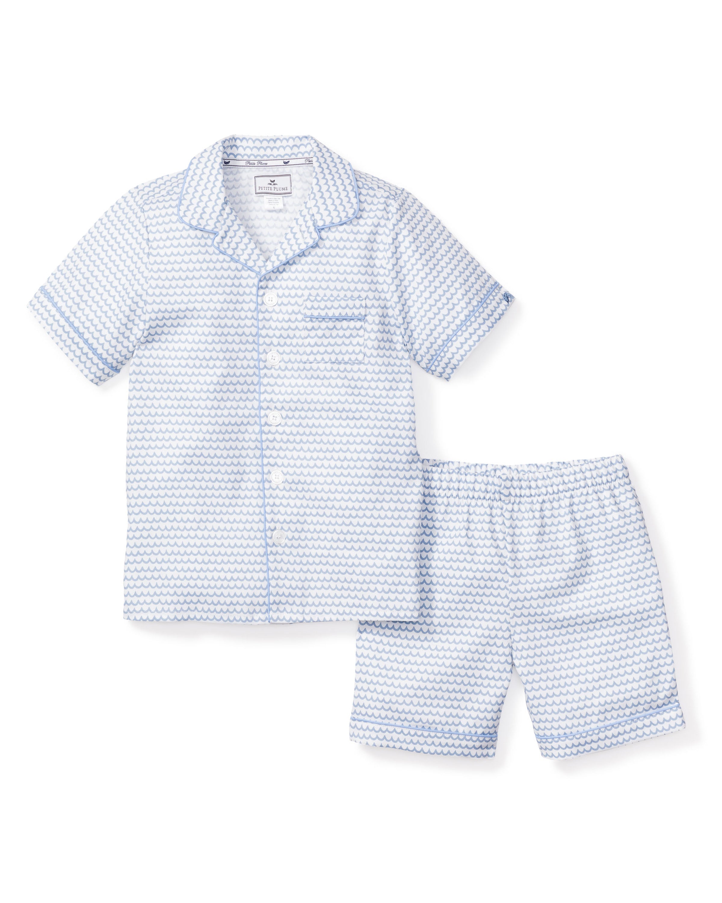 Explore the Kids Twill Pajama Short Set in La Mer by Petite Plume: a light blue patterned short-sleeve set made from premium cotton, featuring a button-up top with a collar and chest pocket, plus matching elastic waistband shorts for comfort and style.