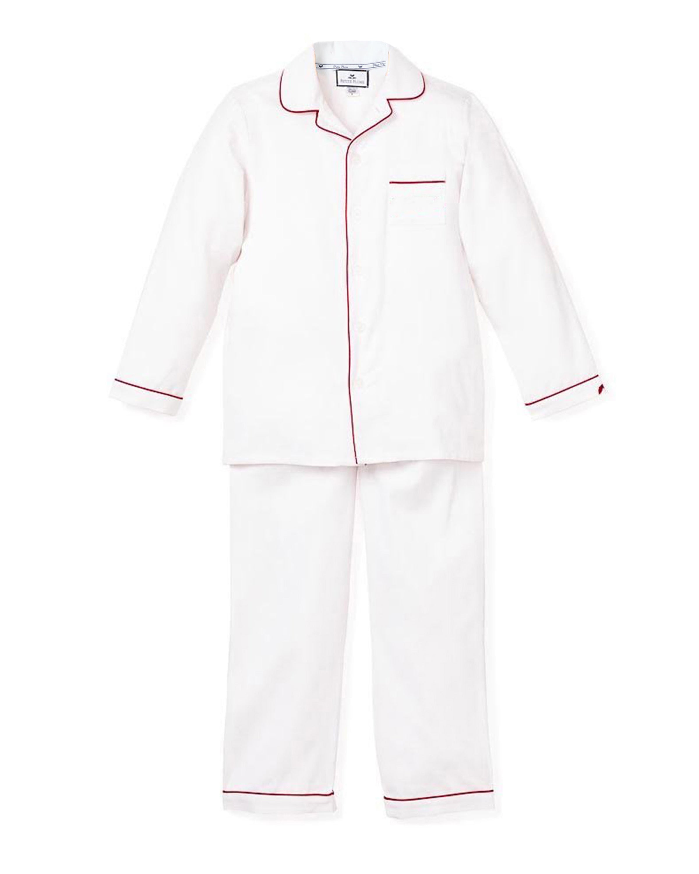 The Petite Plume Kids Twill Pajamas in White with Red Piping are crafted from flame-retardant cotton, featuring a long-sleeved top with notched collar, left chest pocket, and front buttons. The matching pants offer an elegant look with an elastic waistband for ultimate comfort.