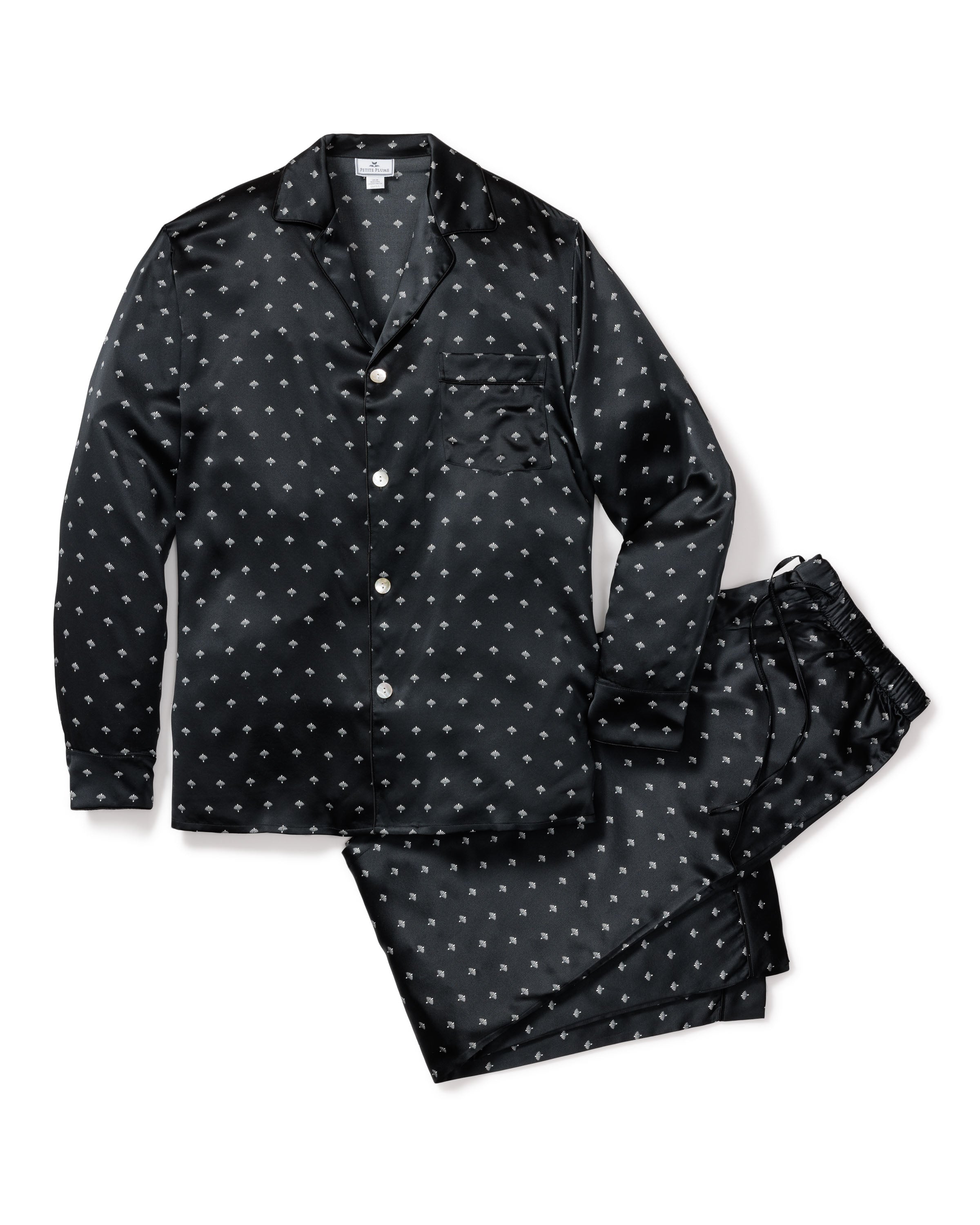 The Mens Silk Pajama Set in Black Art Nouveau by Petite Plume showcases black luxurious pajamas with white polka dots. Made from soft mulberry silk, the set includes a long-sleeve button-up top and pants, elegantly displayed flat against a white background.