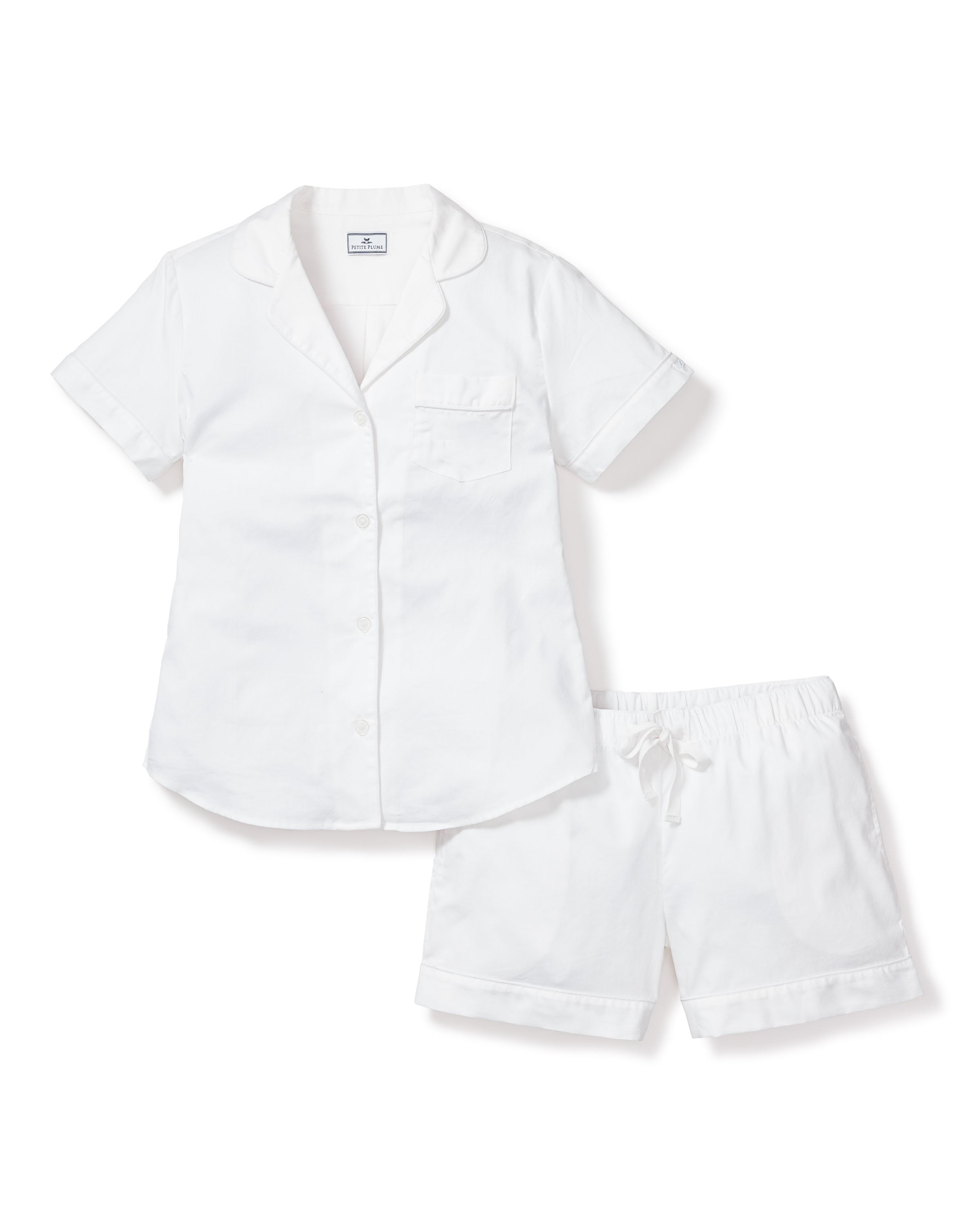 The Womens Twill Pajama Short Set in White from Petite Plume offers luxury sleepwear with a short-sleeve button-up top featuring a pocket and collar, paired with matching drawstring shorts made from the finest quality cotton.