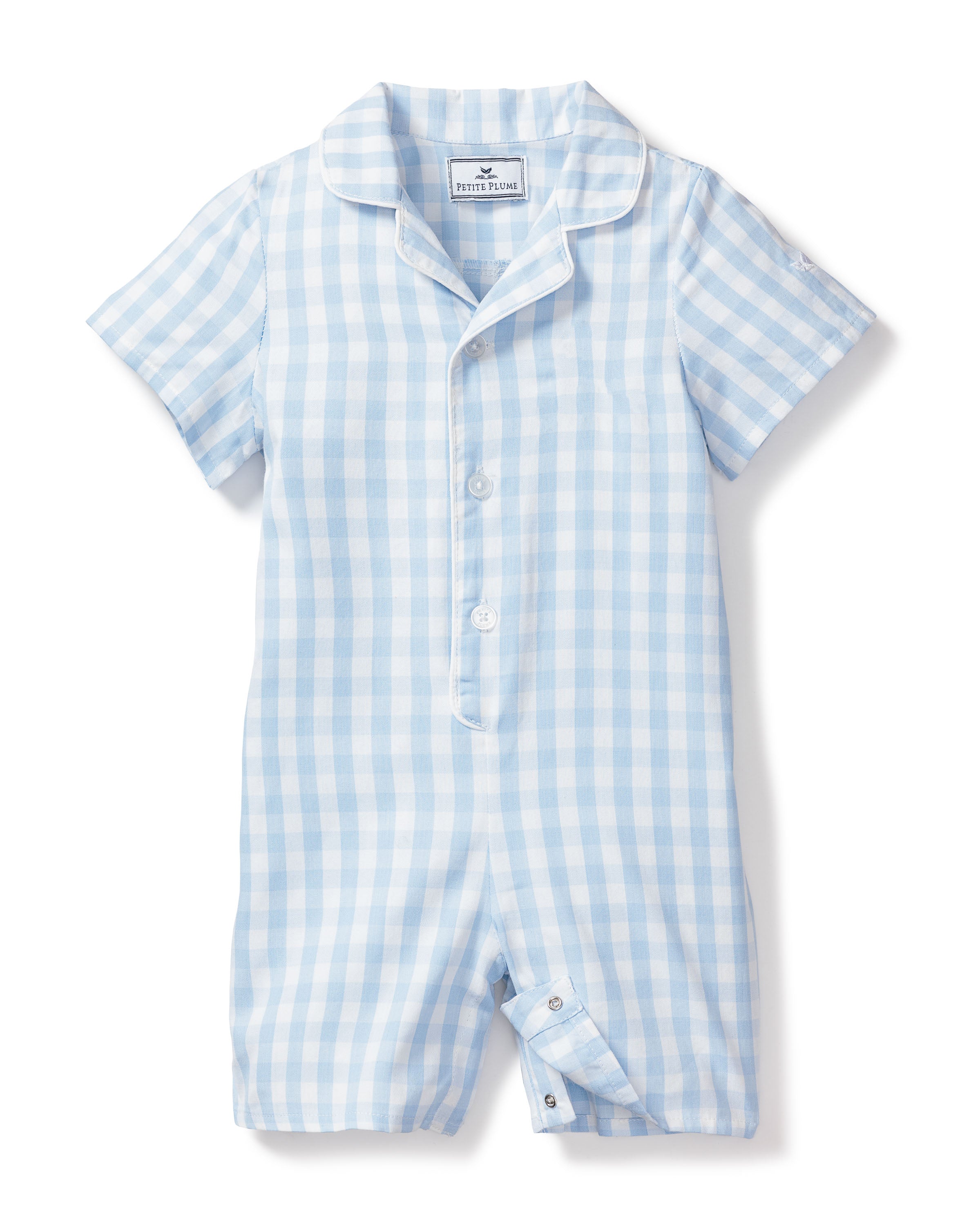 The Babys Twill Summer Romper by Petite Plume features a light blue gingham print with short sleeves and a collar. Crafted from yarn-dyed cotton, it has front buttons and bottom snap closures for easy changing.